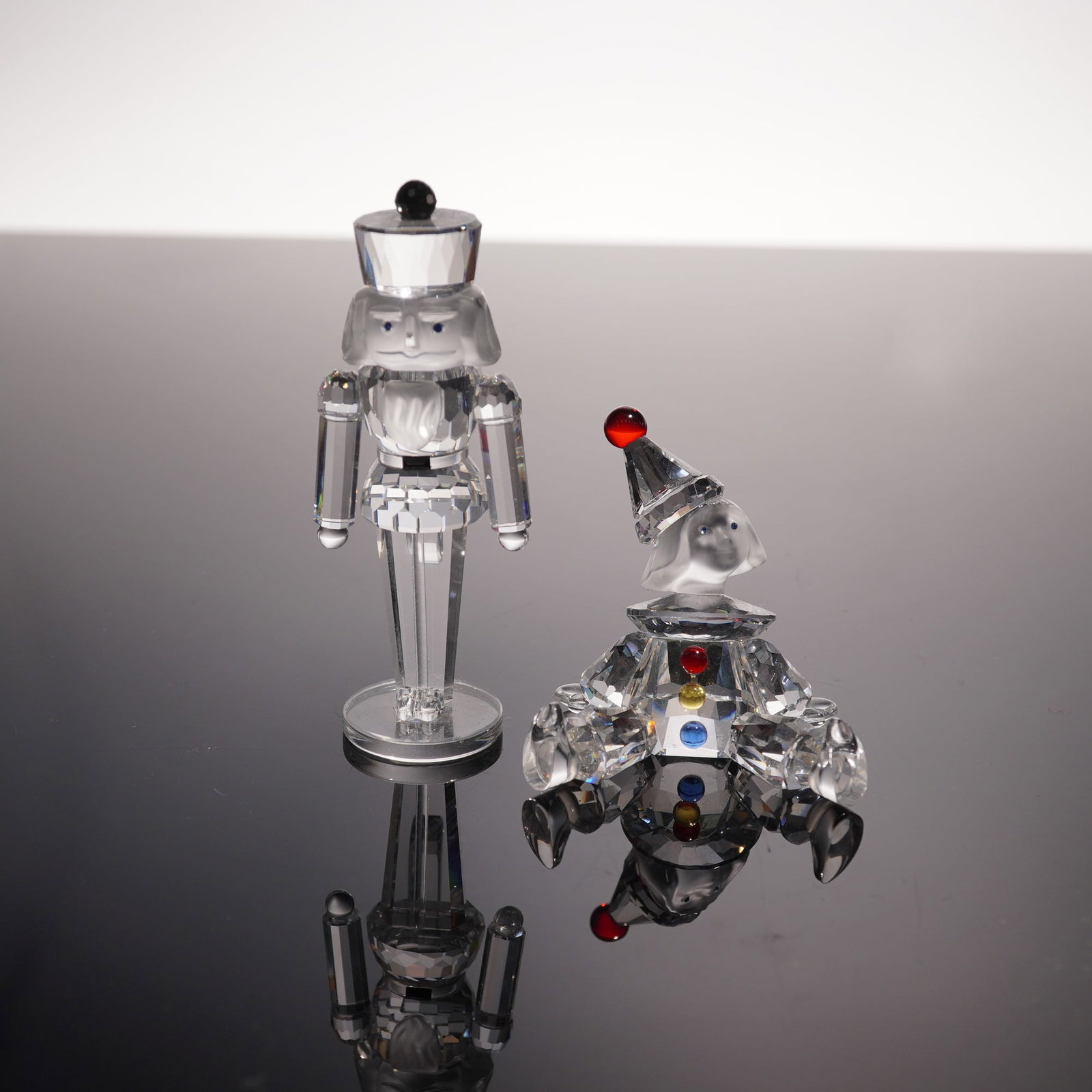 2pc Swarovski Crystal Figurines, Nutcracker Soldier and Puppet: Collection includes Nutcracker Soldier (236714), part of the "Exquisite Accents" theme, crafted in clear crystal with blue eyes, a frosted face, and a black crystal accent on the top of the hat, desig