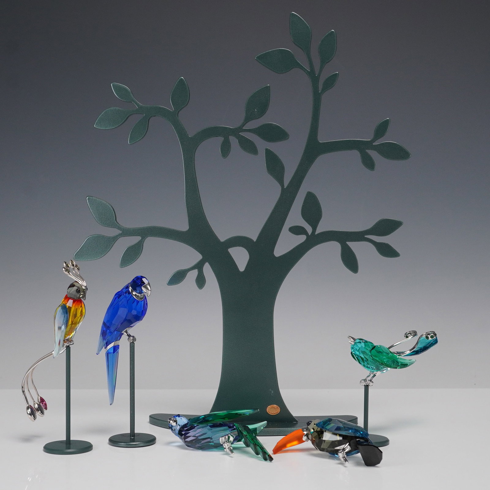 6pc Swarovski Crystal Paradis Birds and Tree Stand: A breathtaking collection of 5 Swarovski Crystal Paradis Birds figurines from the 'Tropical Birds and Parrots' series. Each bird is masterfully crafted in vibrant crystal hues, capturing the brillianc