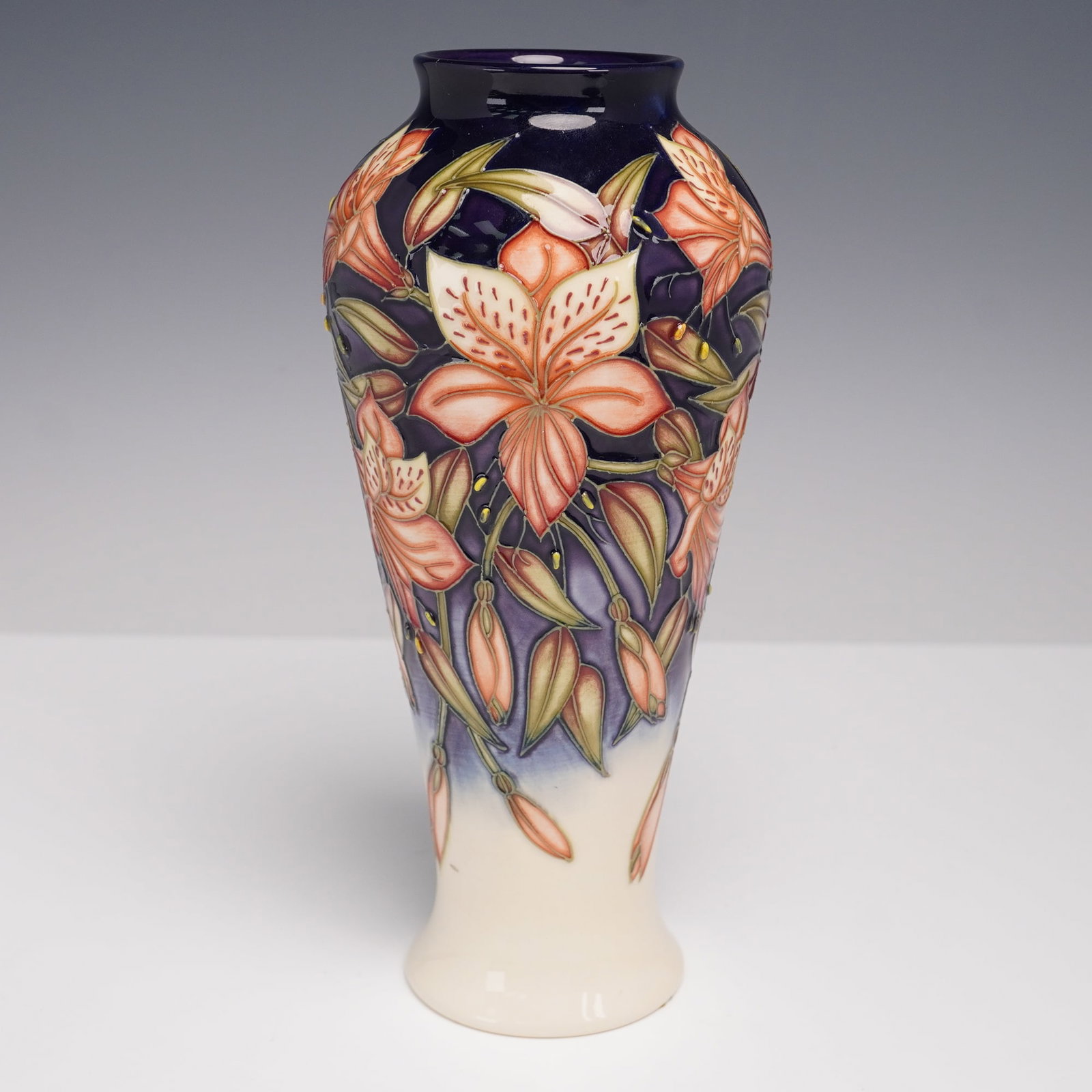 Moorcroft Pottery by Sian Leeper Vase, Peruvian Lily: One of a kind pottery vessel of void form with flaring foot and short neck, Decorated in tube lined relief with a profusion of orange lilies and unopened buds cascading against a deep cobalt ground th