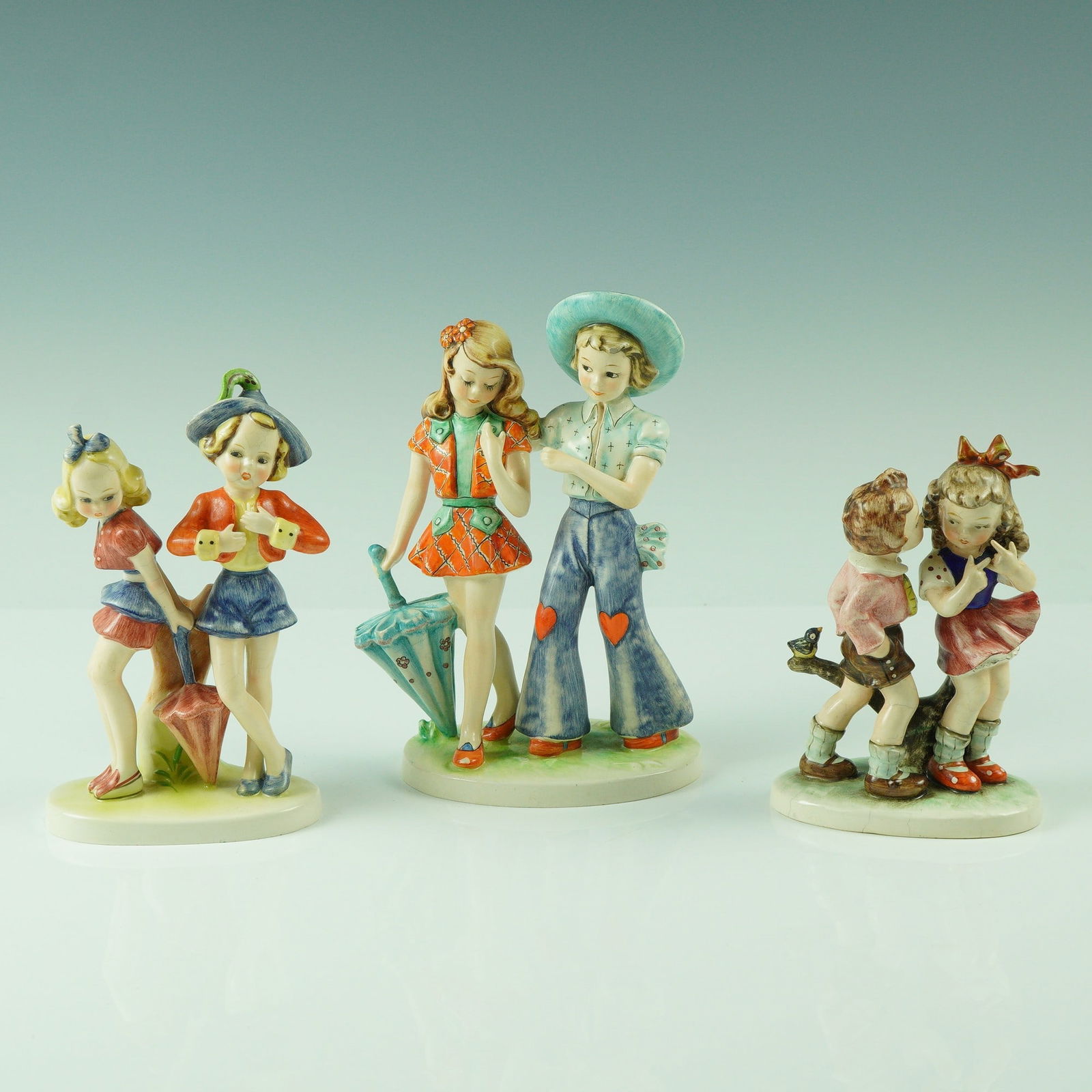 3pc Vintage Goebel Hand-Painted Figurines: A charming group of three vintage German porcelain figurines by Goebel, each finely hand-painted and marked on the underside with the Goebel trademark and "Germany." These whimsical figures capture sc