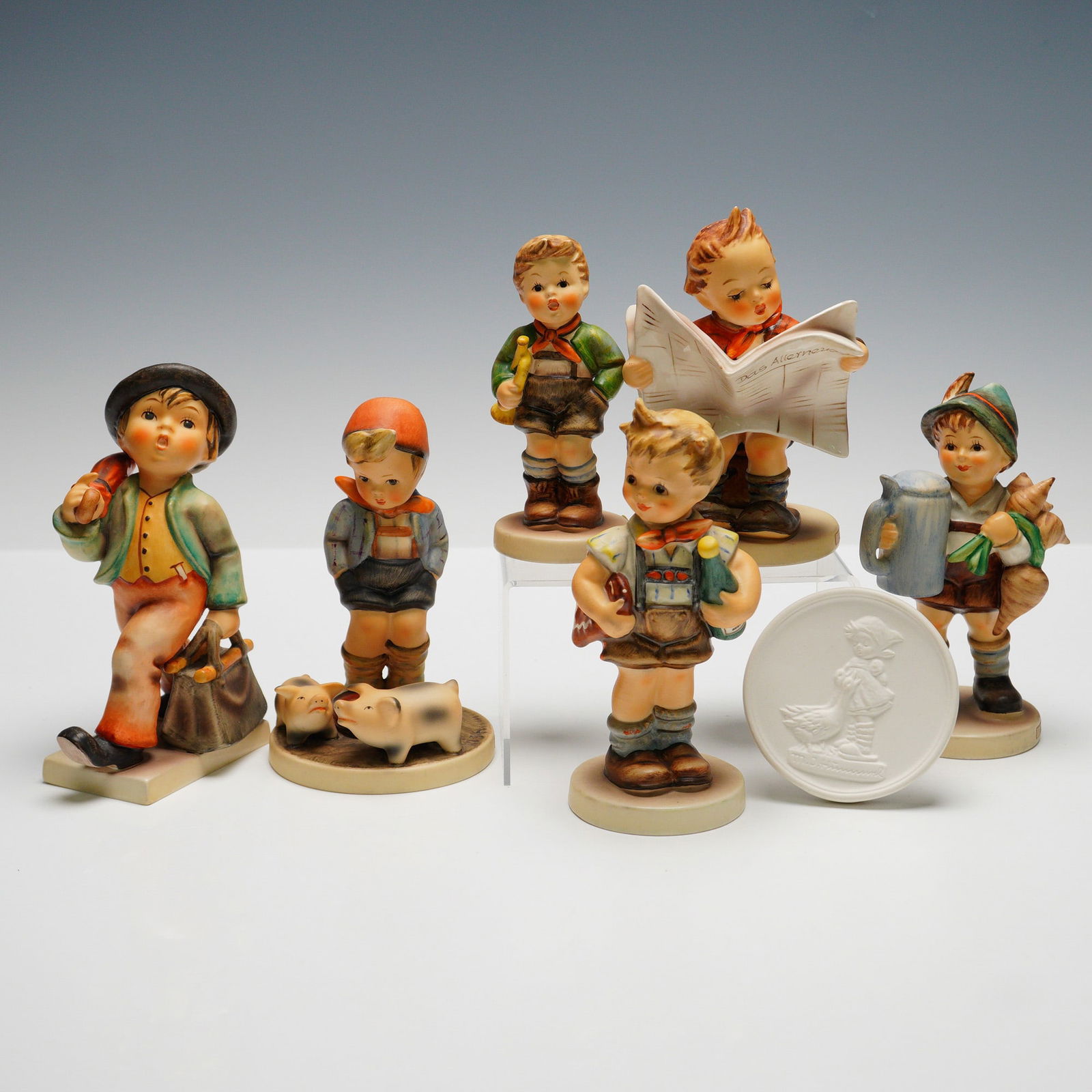 7pc Goebel Hummel Figurines and Plaque: Collection including six figures and one commemorative plaque with original box. Figures consist of "Trumpet Boy" (HUM97), "For Father" (HUM87), "Latest News" (HUM184), "Farm Boy" (HUM66), "Merry Wand