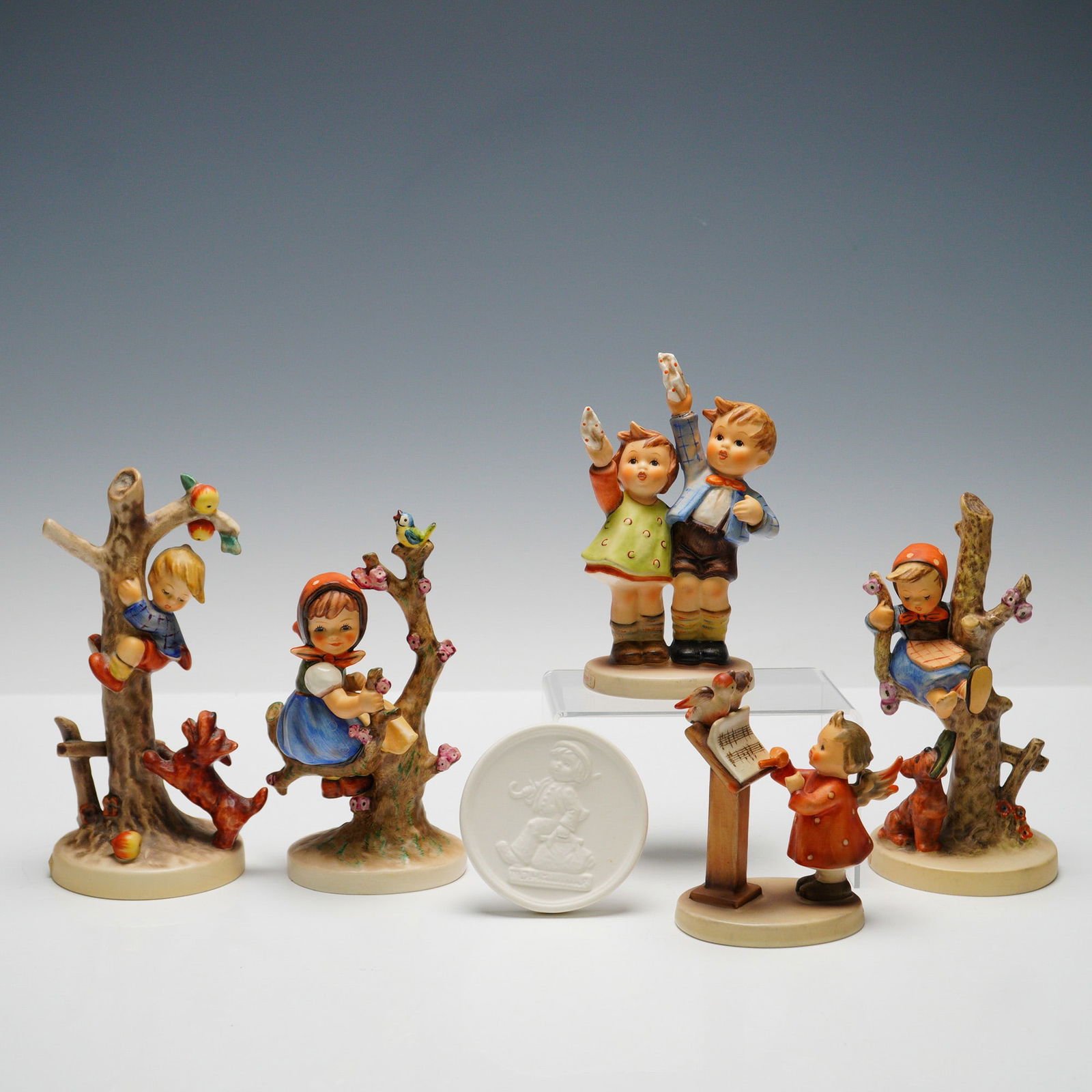 6pc Goebel Hummel Figurines and Plaque: Collection includes five figures and one plaque. Figures consist of "Auf Wiedersehen" (HUM153/0) depicting a boy and girl waving, "Bird Duet" (HUM169) with a girl singing to two birds on a stand, "Out