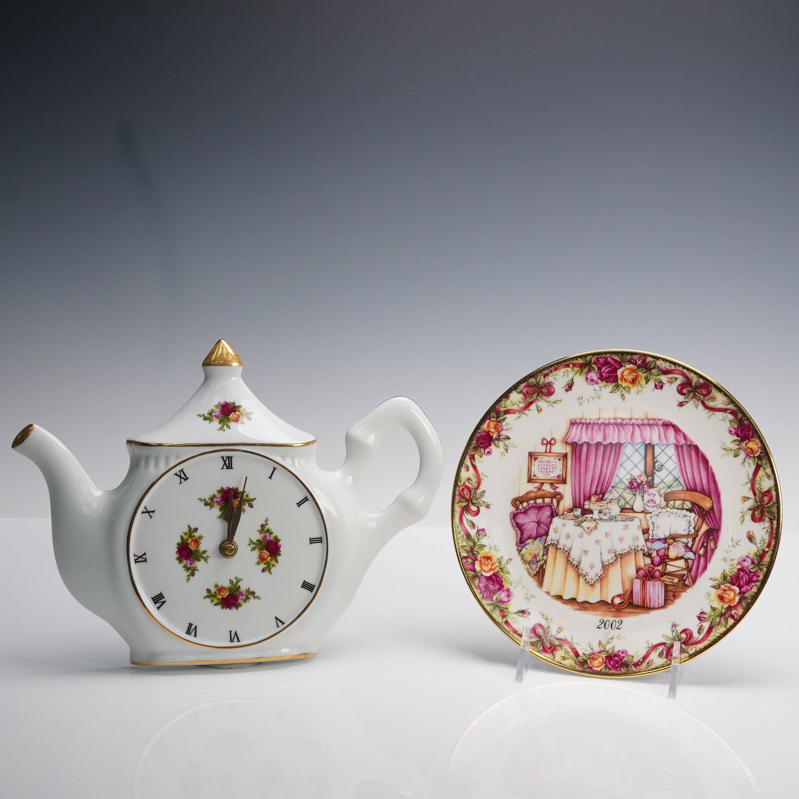 2pc Royal Albert Porcelain Teapot Clock & Celebration Plate, Country Roses: A two piece collection of Bone China featuring the iconic Old Country Roses pattern, including a commemorative Ruby Anniversary Celebration plate with a hanger and a teapot shaped wall clock embellish