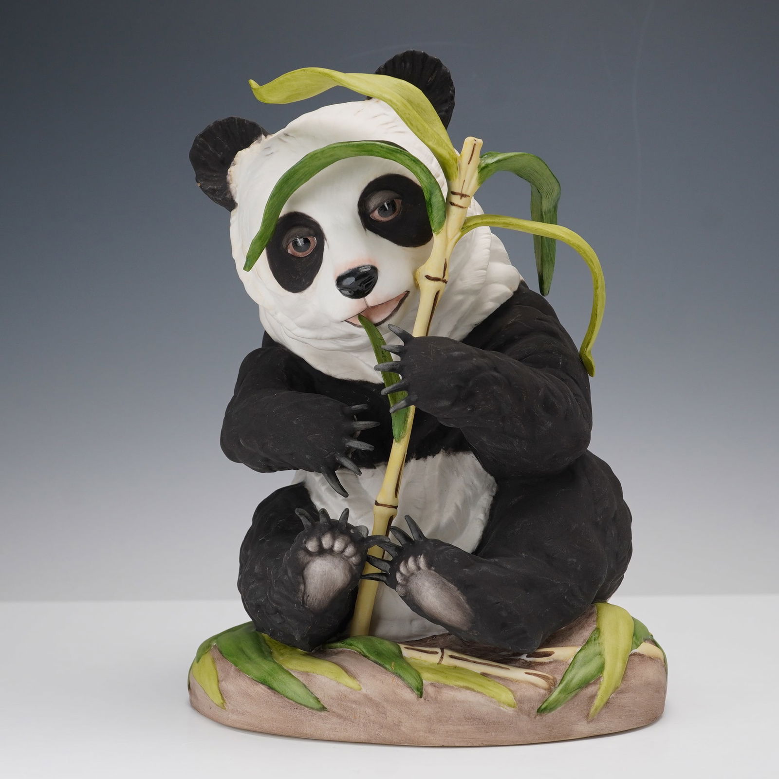 Boehm Porcelain Figurine, Panda Cub Seated: Model number 400-54, made in the U.S.A. by Edward Marshall Boehm. This finely detailed hand-painted sculpture depicts a charming panda cub seated with a stalk of bamboo, accented with naturalistic lea