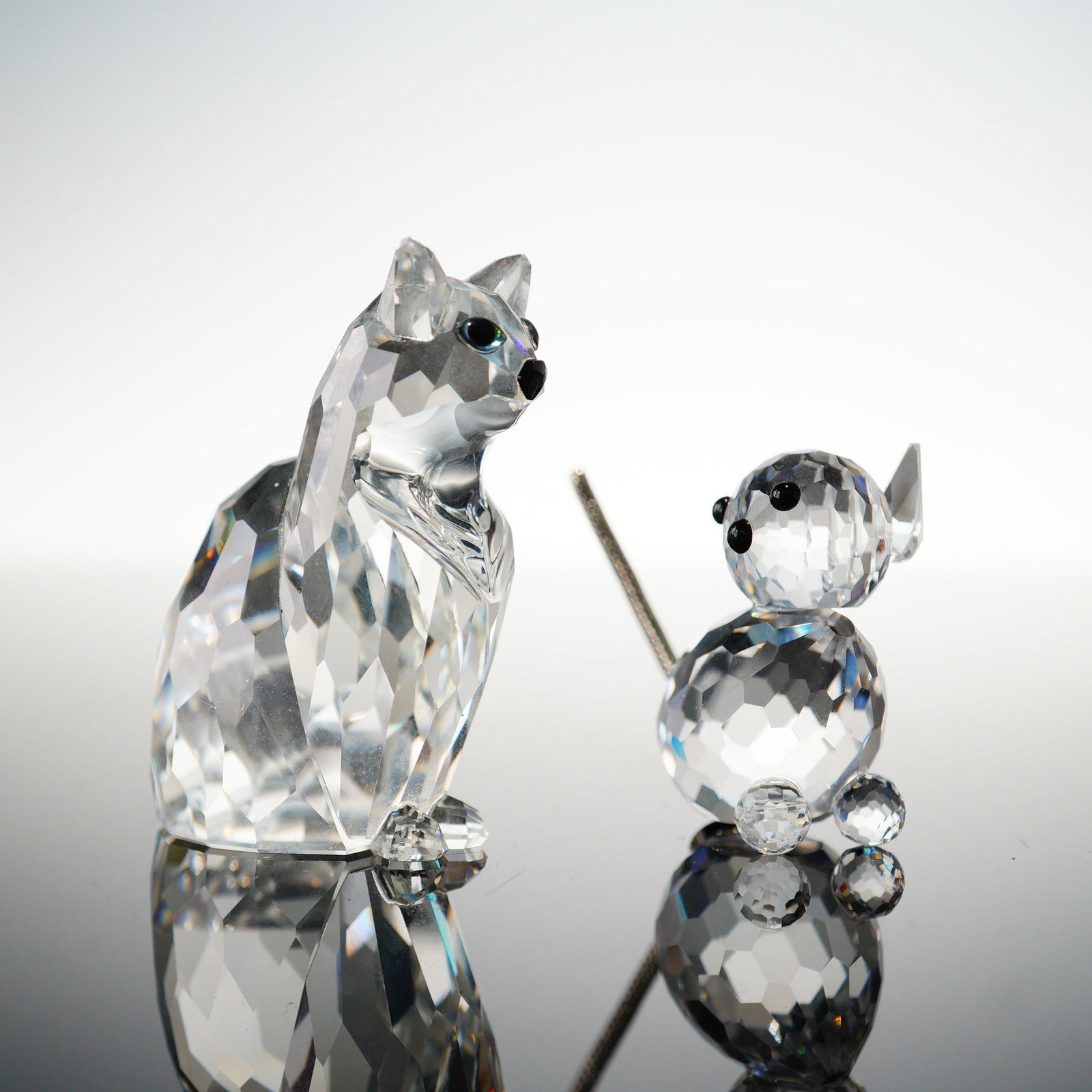 2pc Swarovski Crystal Cat Figurines: This lot includes two Swarovski crystal cats: one Cat Sitting and one Mini Cat. Both are crafted in clear faceted crystal with black crystal accents, and each bears the Swarovski swan mark. The Cat Si