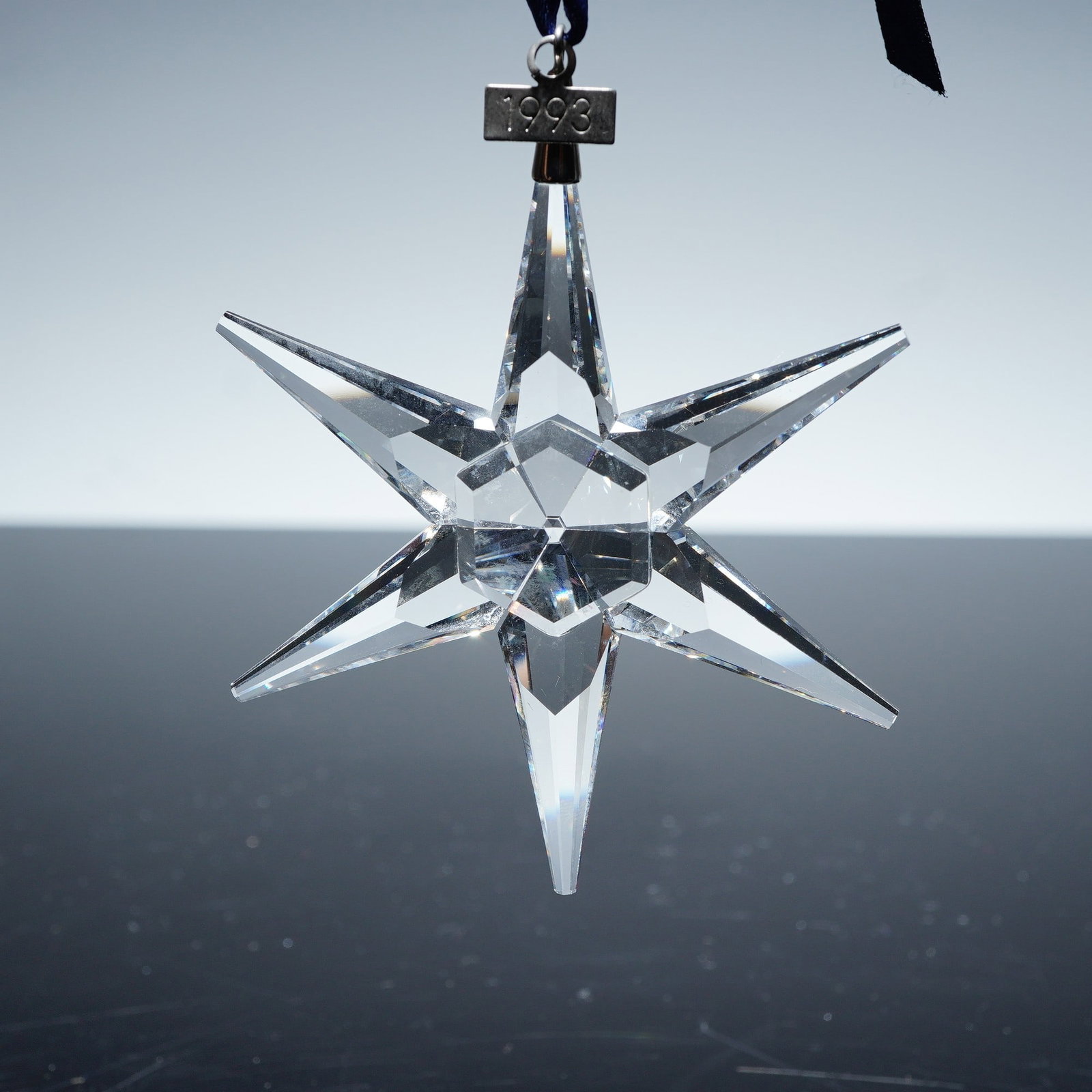 Swarovski Crystal Holiday Ornament, 1993 Annual Edition Star: Swarovski crystal holiday ornament, 1993 annual edition star 174969, showcasing a striking six-pointed clear crystal star with finely cut facets that shimmer brilliantly. The ornament is suspended fro