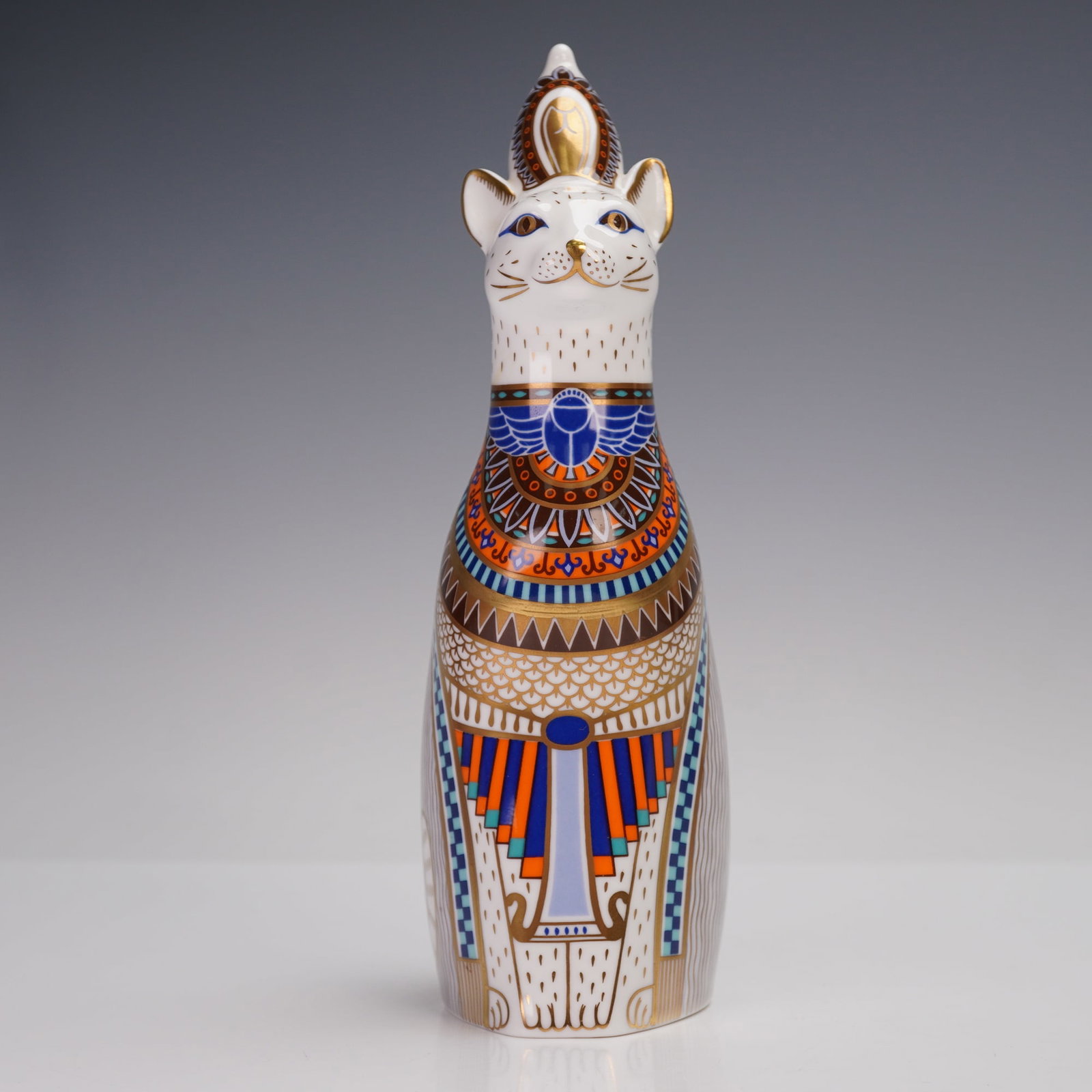 Royal Crown Derby Bone China Royal Cats Paperweight, Egyptian: The stylized cat is crafted in fine English bone china and decorated with intricate geometric and symbolic motifs inspired by ancient Egyptian art, highlighted with cobalt blue, orange, and gold accen