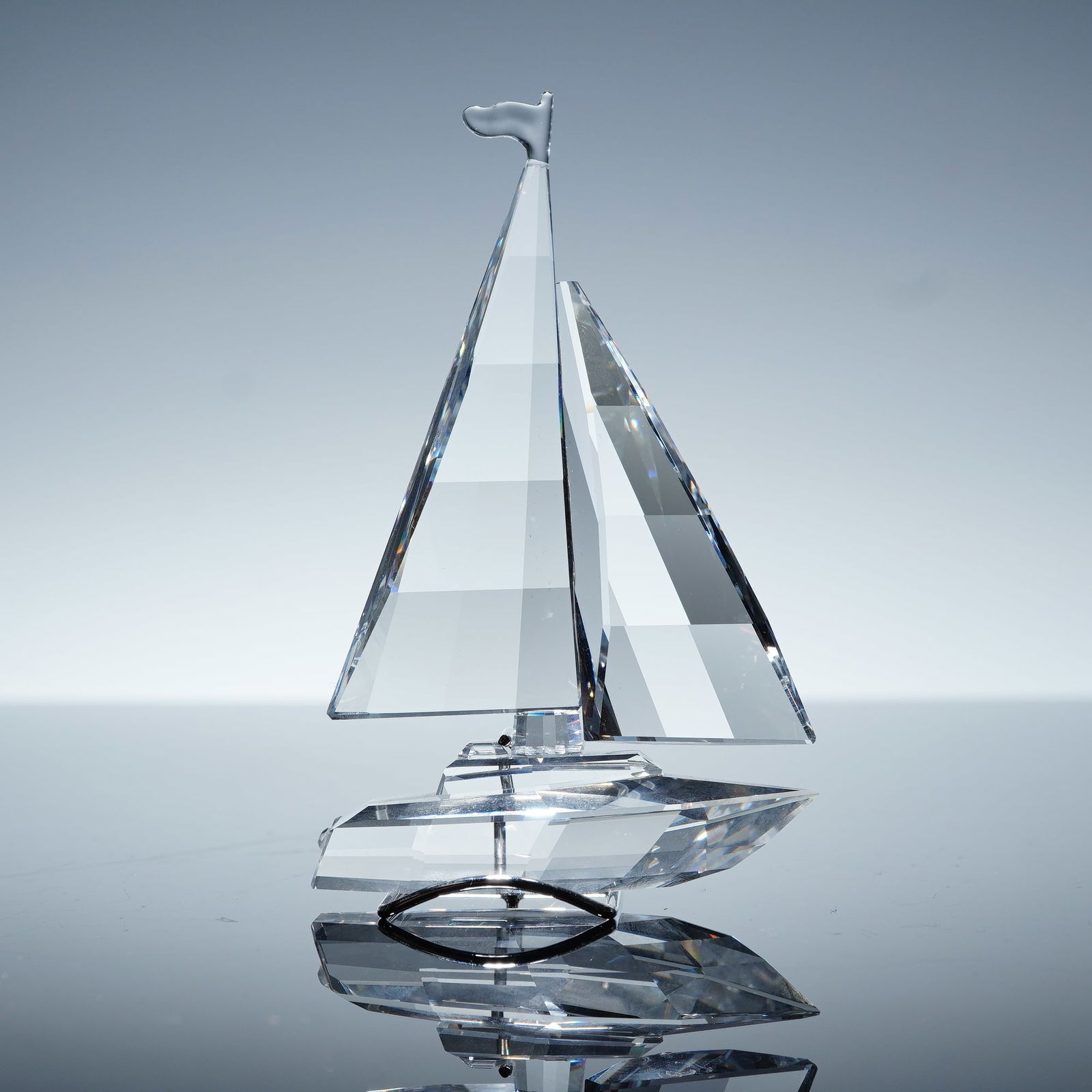 Swarovski Crystal Figurine, Sailboat 183269: Swarovski Silver Crystal figurine 183269, Sailboat, featuring a faceted clear crystal hull and sails with a smooth crystal base. This elegant nautical piece captures the look of a sailboat gliding acr