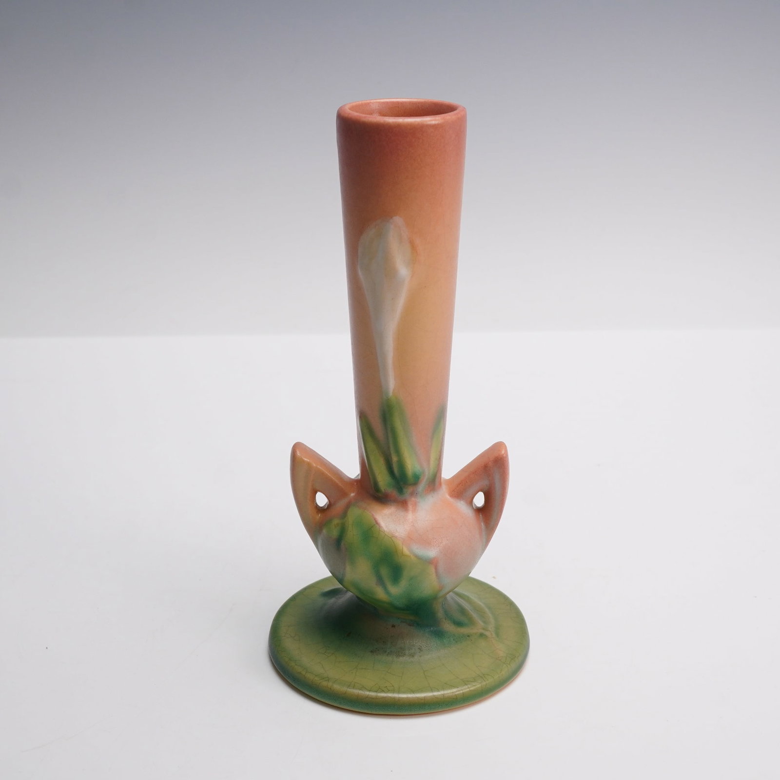 Roseville Pottery Thornapple Bud Vase, Pink: Roseville Thornapple bud vase finished in soft matte pink glaze with raised thornapple blossoms and foliage in creamy white and green. The piece has a slender bud form with subtle Art Deco styling, co