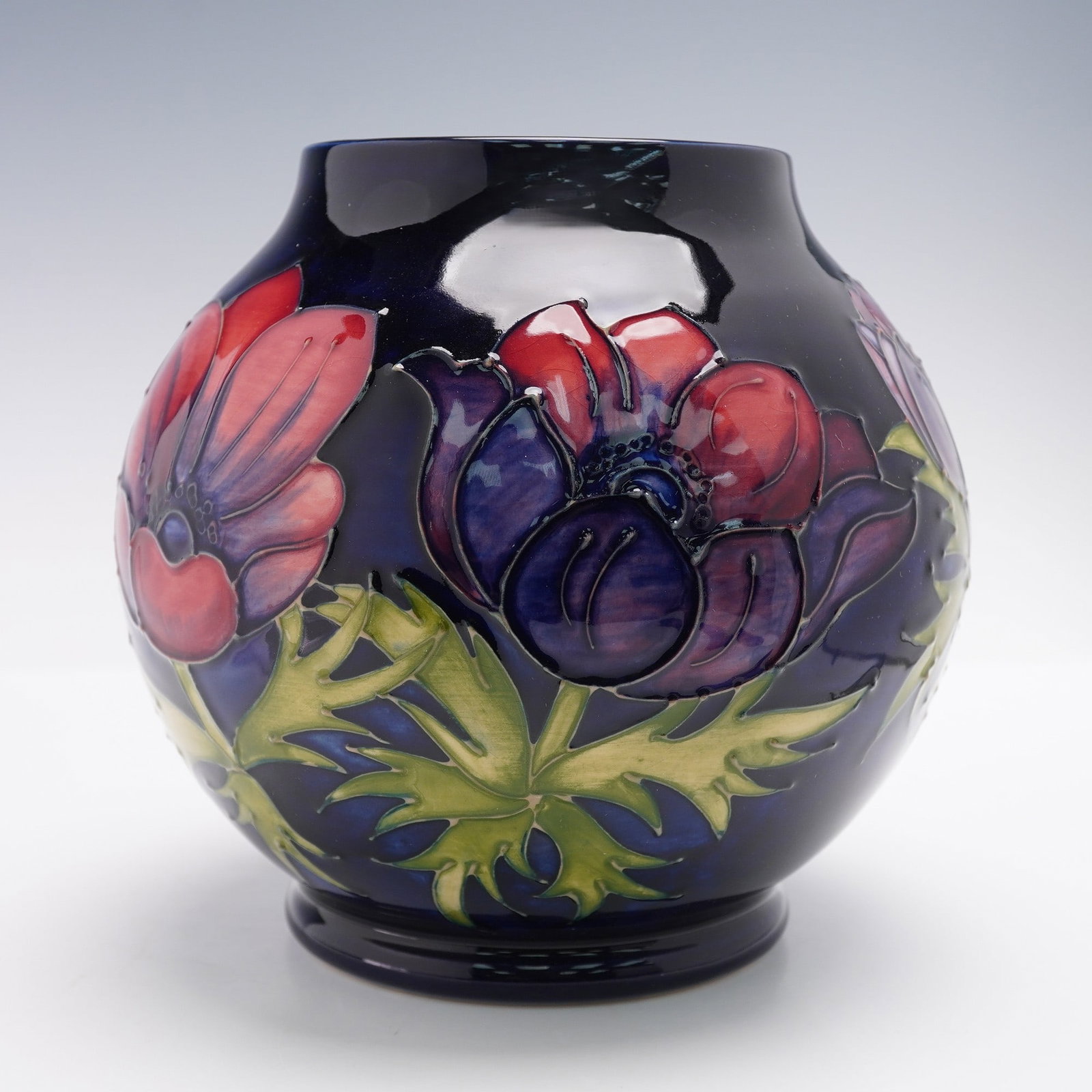 Moorcroft Pottery Vase, Anemone: Decorated in the Anemone pattern, featuring a cobalt-blue ground with tubelined red, purple, and blue anemone flowers and green foliage in relief. The underside bears the impressed Moorcroft stamp alo