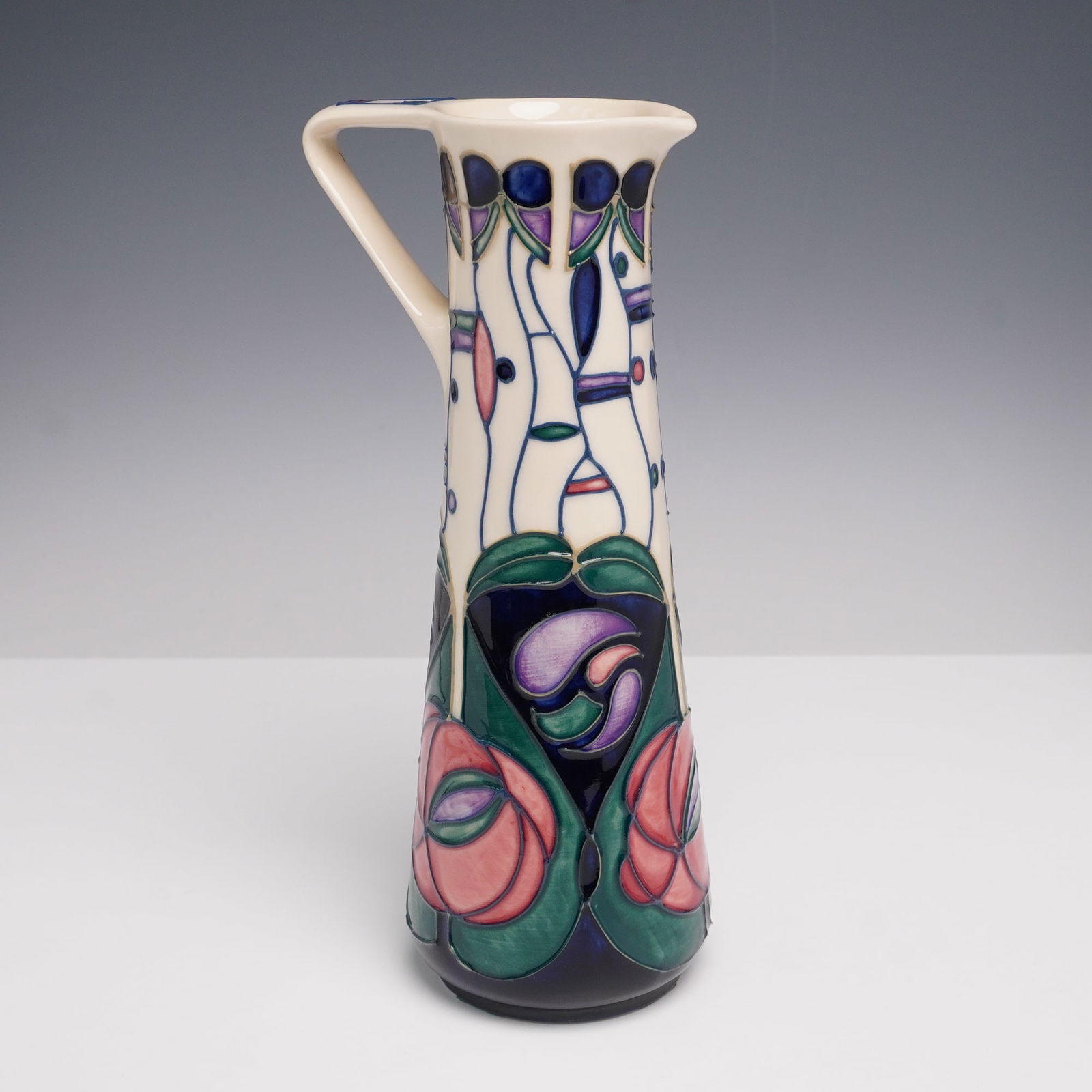 Moorcroft Pottery by Rachel Bishop Jug Tribute to Charles Rennie Mackintosh: A carefully designed vessel attributed to Charles Rennie Mackintosh (Scottish 1868-1928) stained glass roses. The body is decorated with tube lined stylized rose motifs in soft pink and lavender with