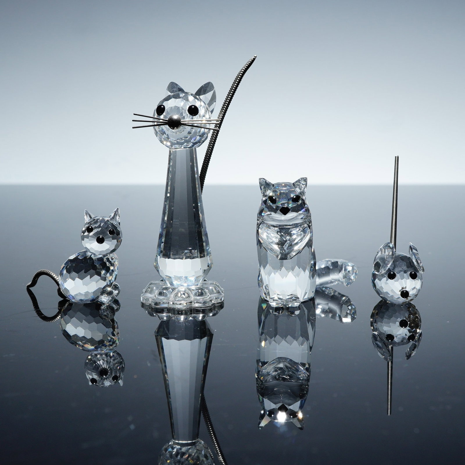 4pc Swarovski Crystal Cat and Mouse Figurines: A delightful collection of Swarovski crystal featuring four animal figures. Included are three cats in varying designs and one small mouse, all marked with the Swarovski logo. Notably, one of the cat 