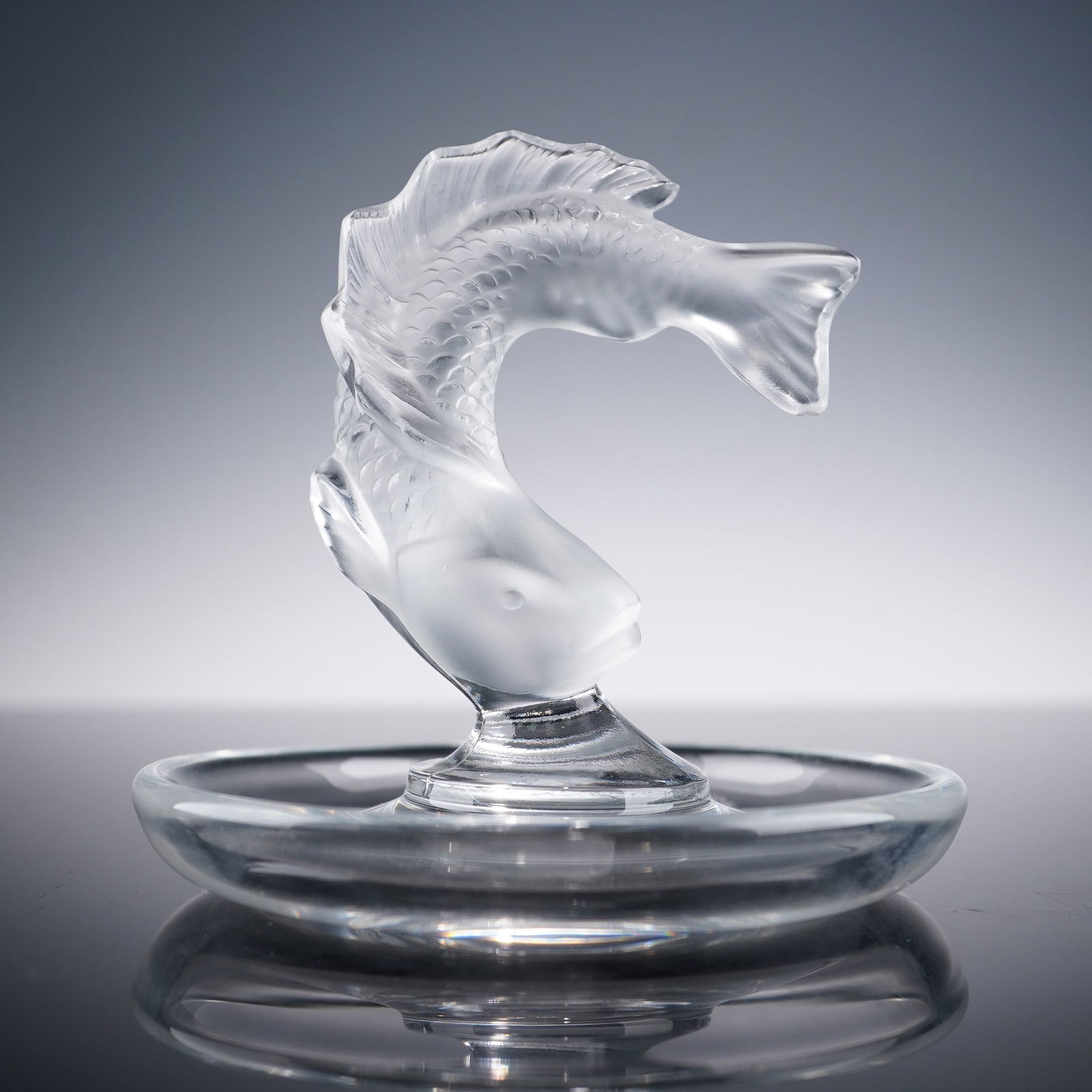 Lalique Crystal Round Pin Tray, Goujon: Lalique crystal round pin tray featuring the Goujon fish design with a frosted crystal fish leaping from the center of a clear circular dish. Signed Lalique France on the underside. This piece showcas