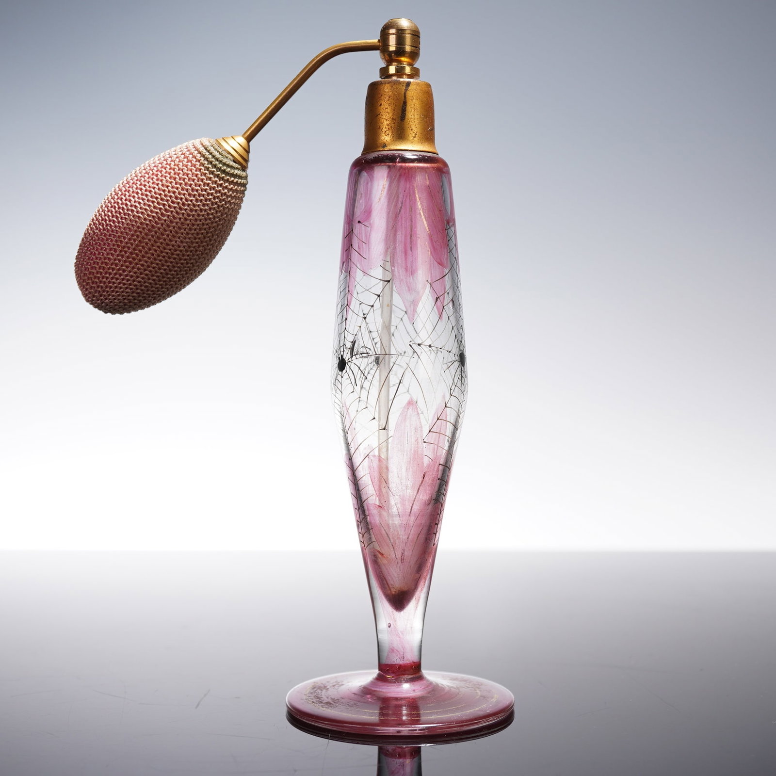 Pink Glass Perfume Atomizer with Spider Design: A pink-tinted glass perfume atomizer featuring hand-painted floral petals accented with a finely rendered spiderweb and small spider detail. This is a very unusual design, combining traditional floral