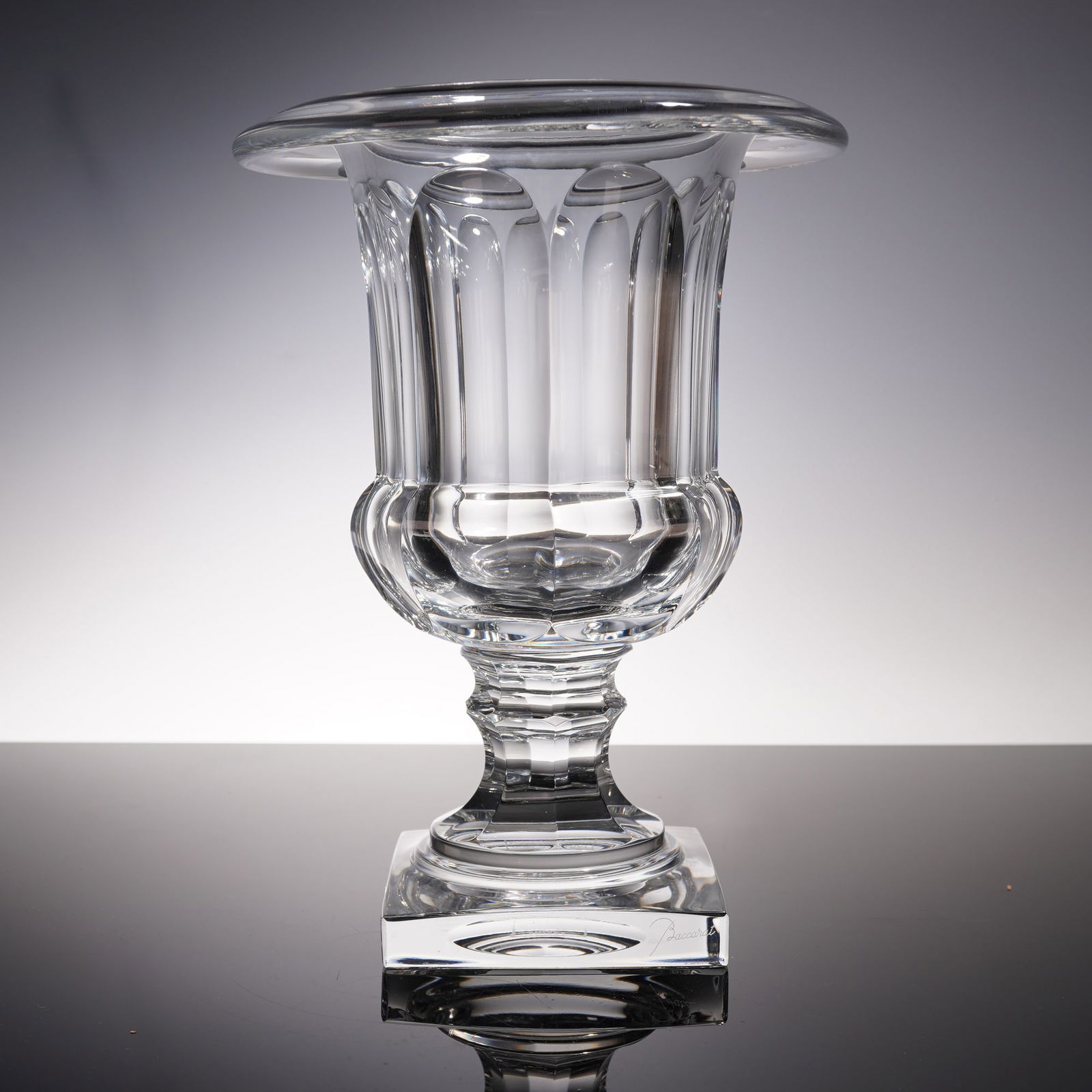 Baccarat Mussee Des Cristalleries Urn: Reproduction urn featuring a fluted baluster form with elongated vertical panels and a rounded gadrooned lower body rising on a faceted stem. The urn rests upon a square plinth base etched with the Mu