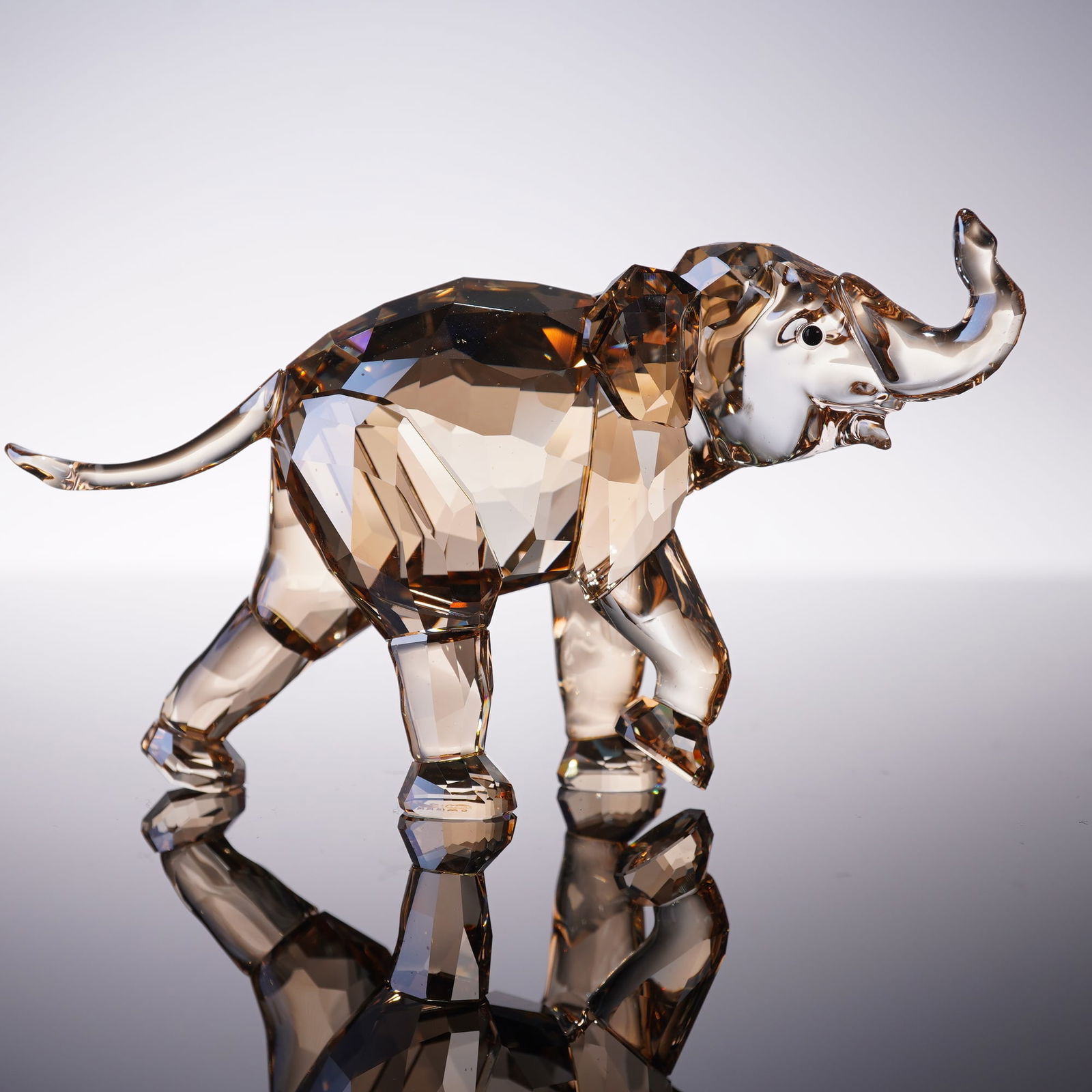 Swarovski Crystal Figurine, Companion Young Elephant: Crafted in Crystal Light Sand with trunk raised. Designed to accompany the SCS Annual Edition 2013 Elephant Cinta, this figurine was available exclusively to Swarovski Crystal Society members in 2013.