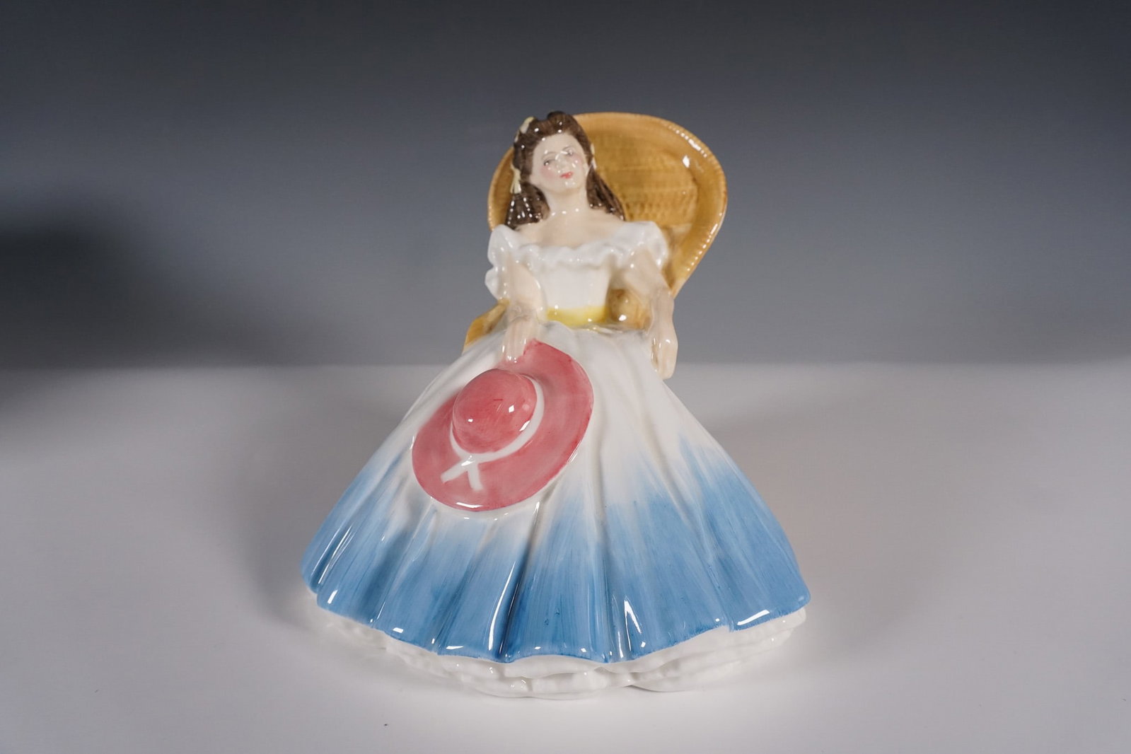 Royal Doulton Figurine, Annabel HN 3273: Royal Doulton fine bone china figurine titled Annabel, HN 3273. Designed by Nada Pedley, this elegant figurine features a young lady seated in a wicker chair, dressed in a flowing blue and white gown 