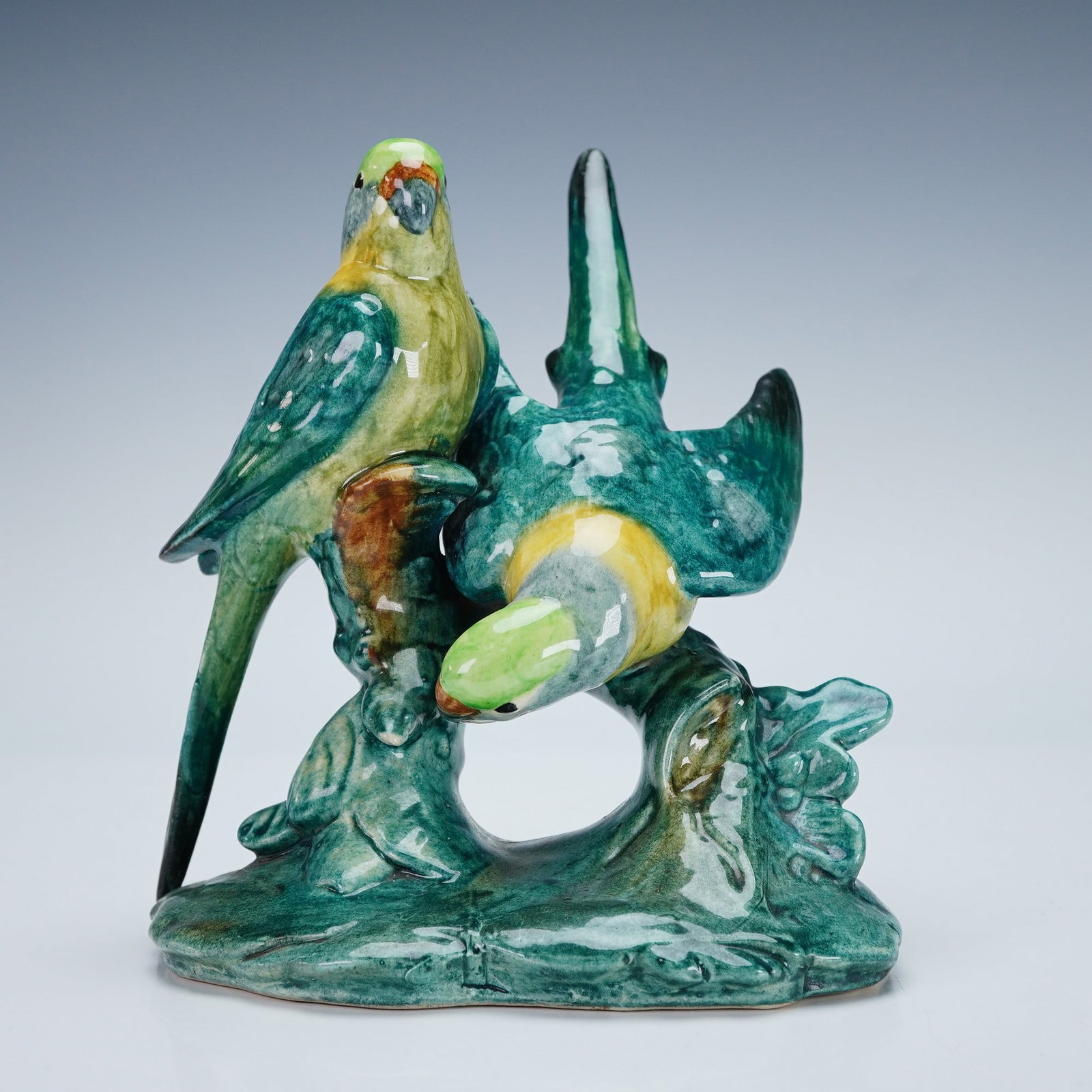 Stangl Pottery Figurine, Double Parakeets: A lovely hand painted figure modeled as a pair of parakeets perched on a naturalistic base. The composition captures the parrots in dynamic postures, one upright and the other arching downward. Stangl