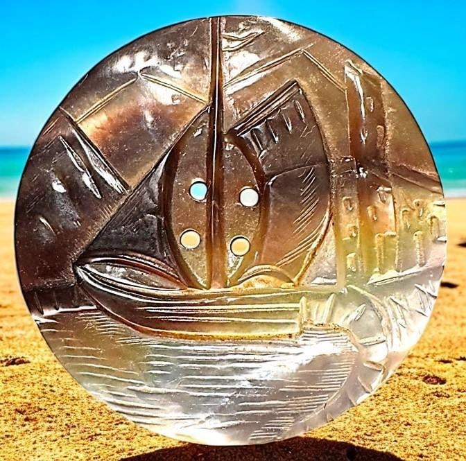 A division one carved and shaded pearl pictorial button: 1 Large 19th century hand carved ship sew thru example. This is a wonderfully detailed carved in low relief sailing vessel on white pearl with beautiful chatoyant brown shading. Great example and in f
