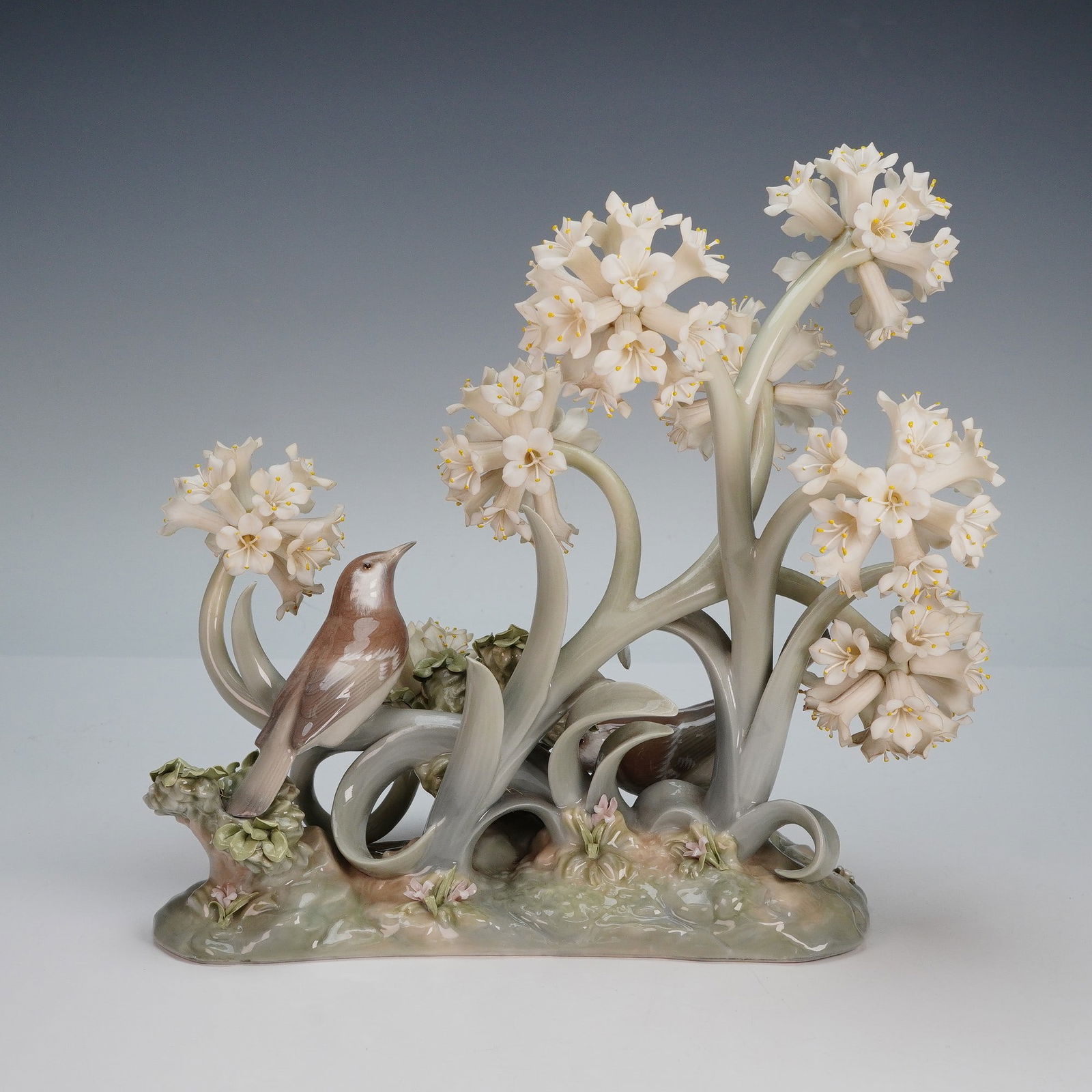 Lladro Porcelain Figurine, The Forest 1001243: Limited edition, exquisite composition featuring delicate trumpet shaped white flowers with yellow stamens and perched birds among elegant swirling foliage. Lladro backstamp. Artist: Antonio Ballester