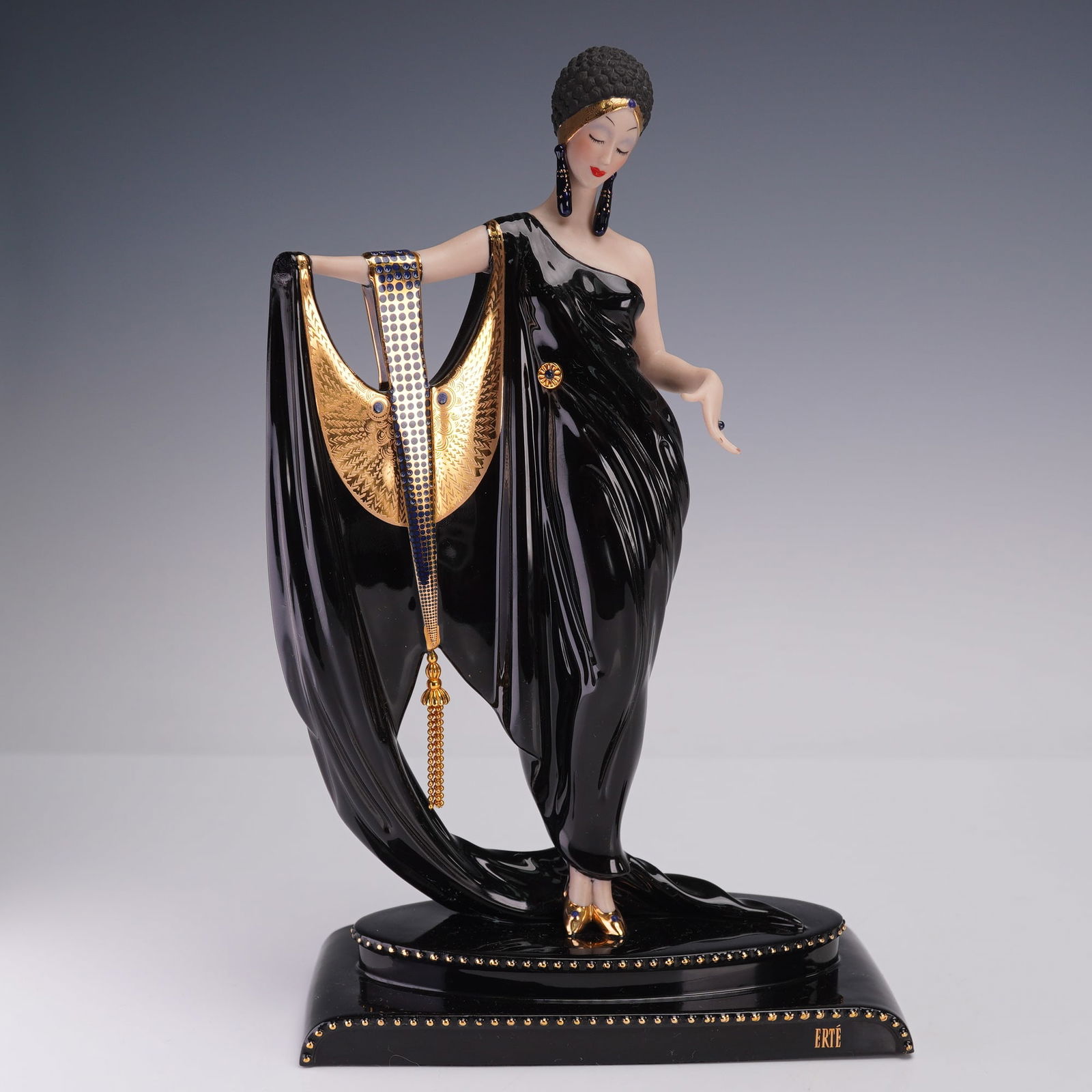 Limited Edition The Franklin Mint House of Erte Figurine, Glamour: Portrays an elegant woman with closed eyes and bright red lips, wearing a flowing black gown with golden detailing and a dramatic drape adorned with jeweled accents. She stands gracefully on a studded
