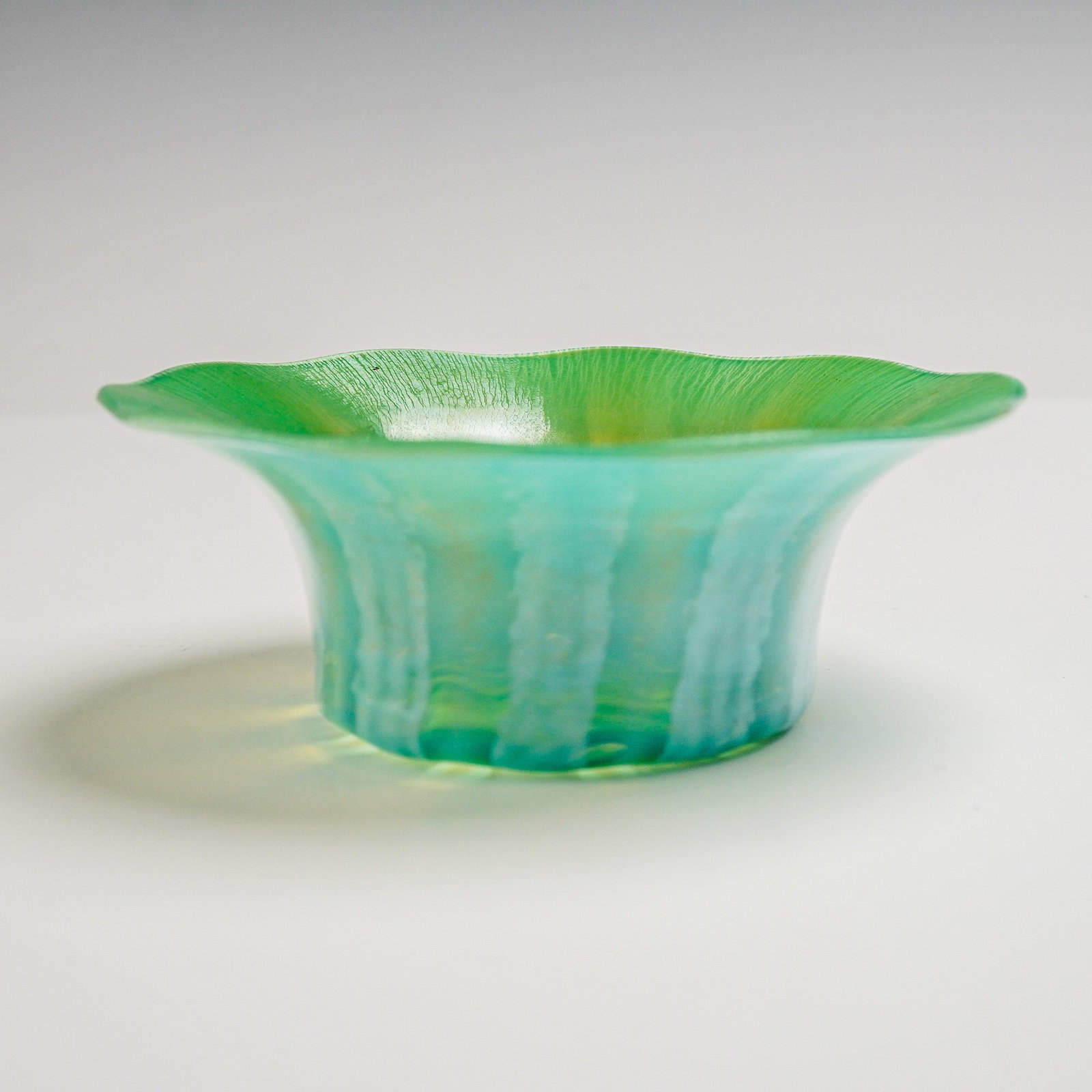 Louis Comfort Tiffany Favrile Glass Pastel Iridescent Bowl: Pastel iridescent bowl with a gently flared and scalloped rim, featuring a luminous green interior transitioning to a blue exterior. The surface displays subtle striations and textured detailing, with