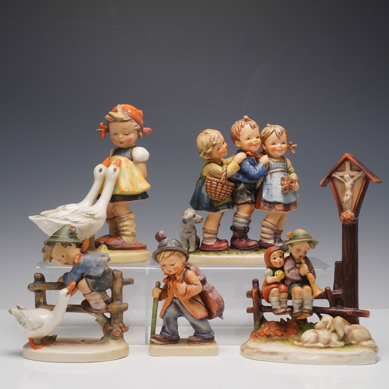 5pc Group of Collectible Goebel Hummel Figurines: Group of five Goebel Hummel porcelain figurines, hand-painted in polychrome glazes and marked on the bases. The lot includes WAYSIDE DEVOTION 28 depicting two children at a wayside crucifix shrine, TH