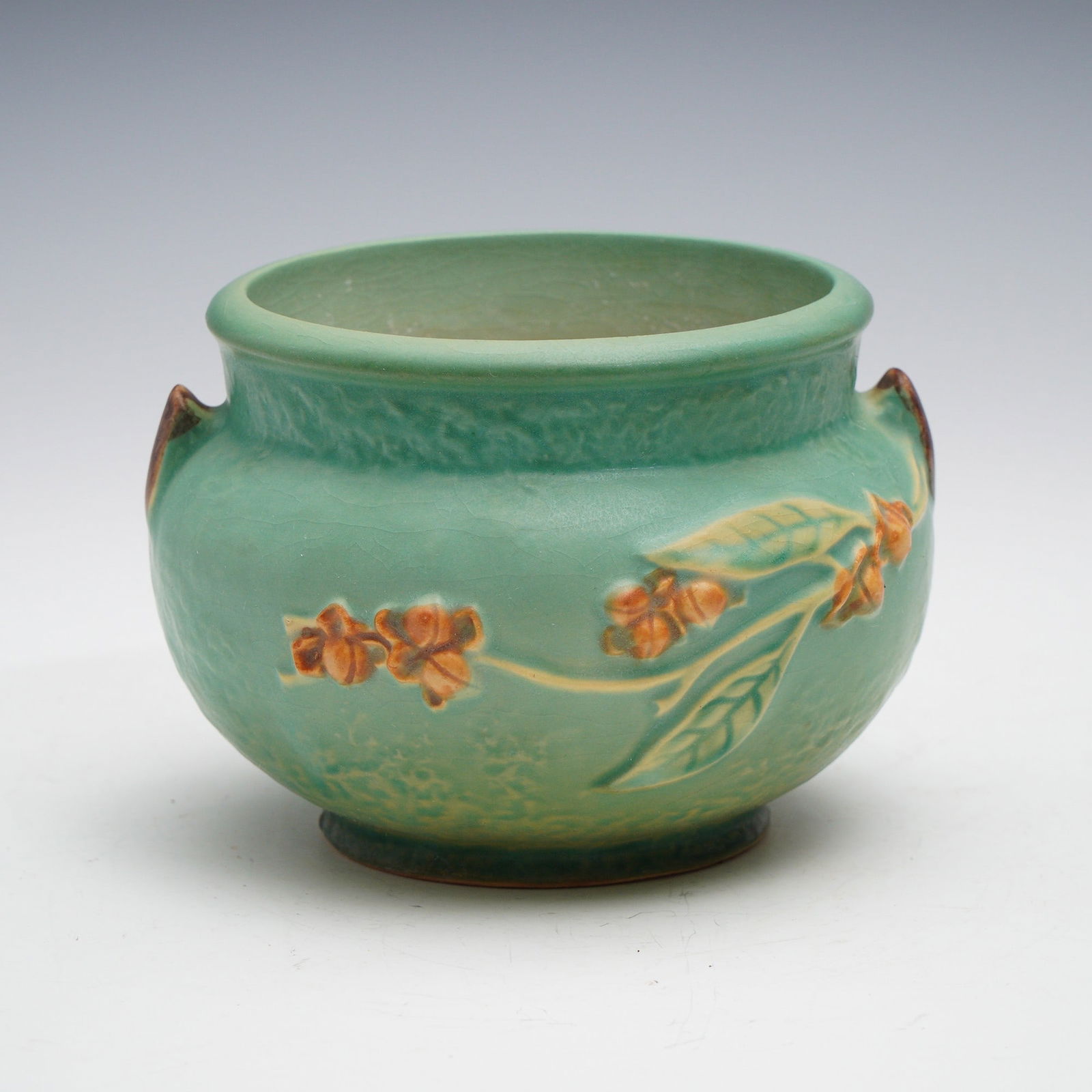 Roseville Pottery Bittersweet Jardiniere: Roseville Pottery Bittersweet jardiniere, shape number 800. This round form jardiniere features a soft green ground with embossed bittersweet vine decoration in warm orange and brown tones, accented b