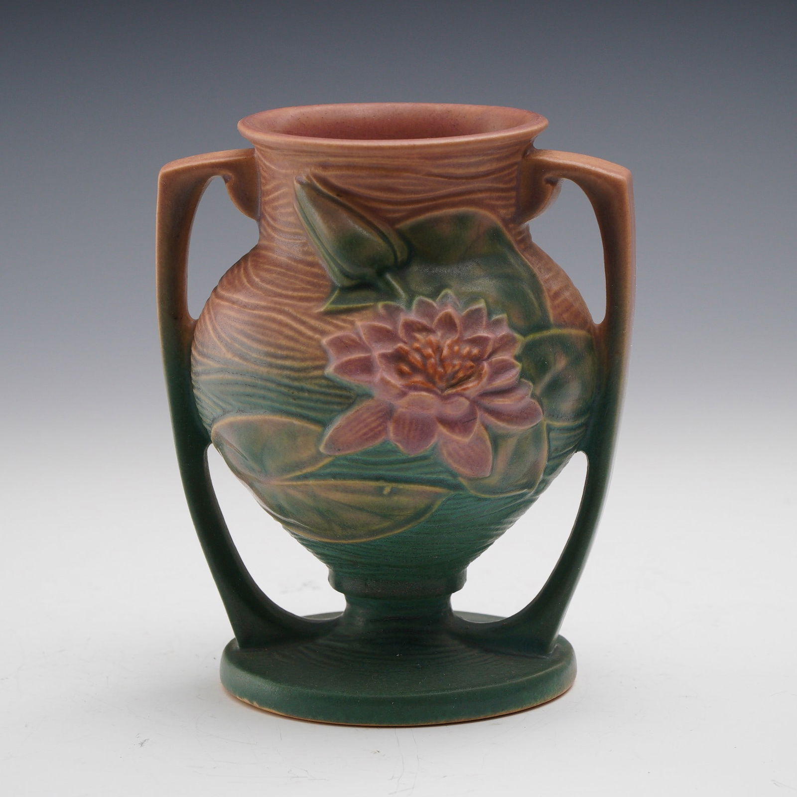 Roseville Pottery Water Lily Vase: An arresting example of American art pottery, this Roseville Water Lily vase features a beautifully modeled pink water lily in full bloom, framed by raised green leaves against a textured background o