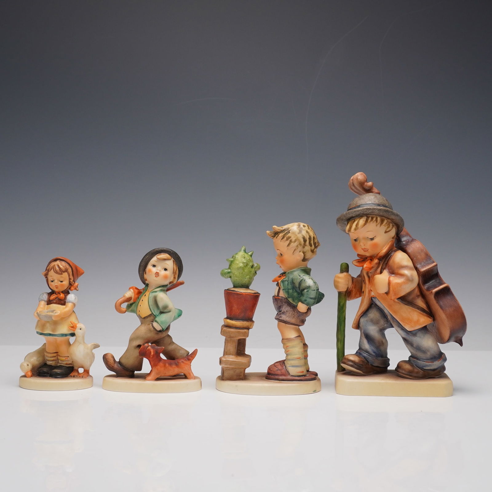 4pc Goebel Hummel Figurines: Collection of four Goebel Hummel figurines. Includes Be Patient Hummel, depicting a girl with geese, Strolling Along showing a boy with umbrella and dog, Confidentially, a boy peering at a cactus in a