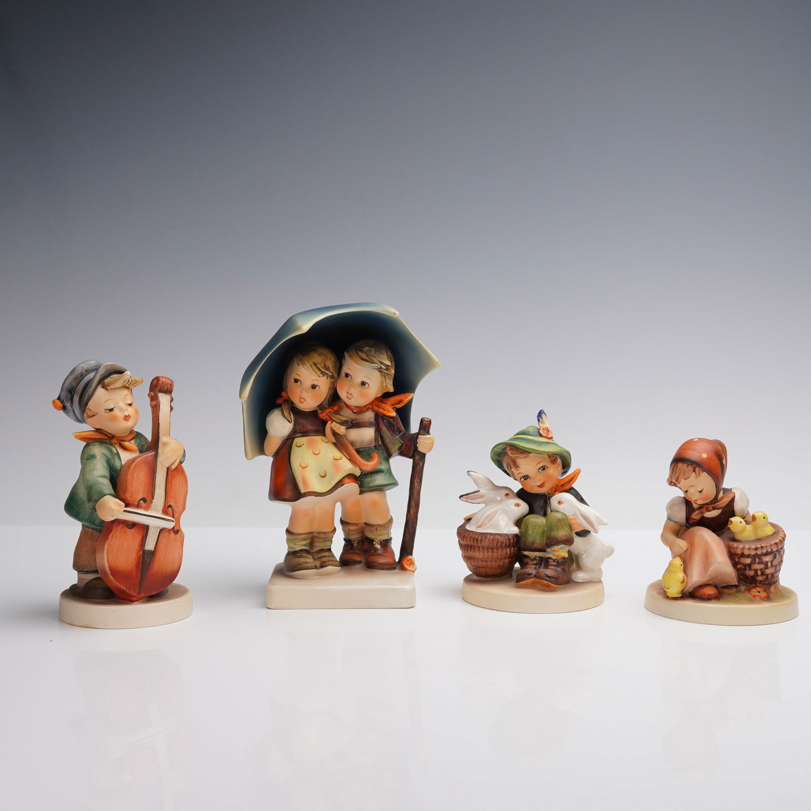 4pc Goebel Hummel Rural Figurines, Stormy Weather & More: Includes "Little Cellist" #89, depicting a young boy playing a cello; "Stormy Weather" #71, featuring a boy and girl sheltered under a large umbrella; "Playmates" #58/0, showing a boy in a green hat s