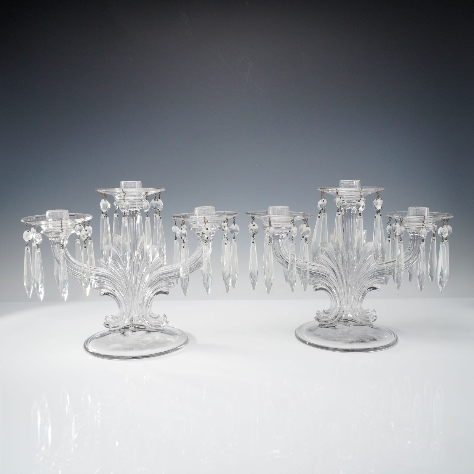 Pair of Fostoria Baroque Three-Light Candelabras: Elegant matched pair from Fostoria's Baroque line, each with a scroll-worked central standard branching to three candle cups. Clear crystal throughout; each sconce is fitted with a removable ring hung