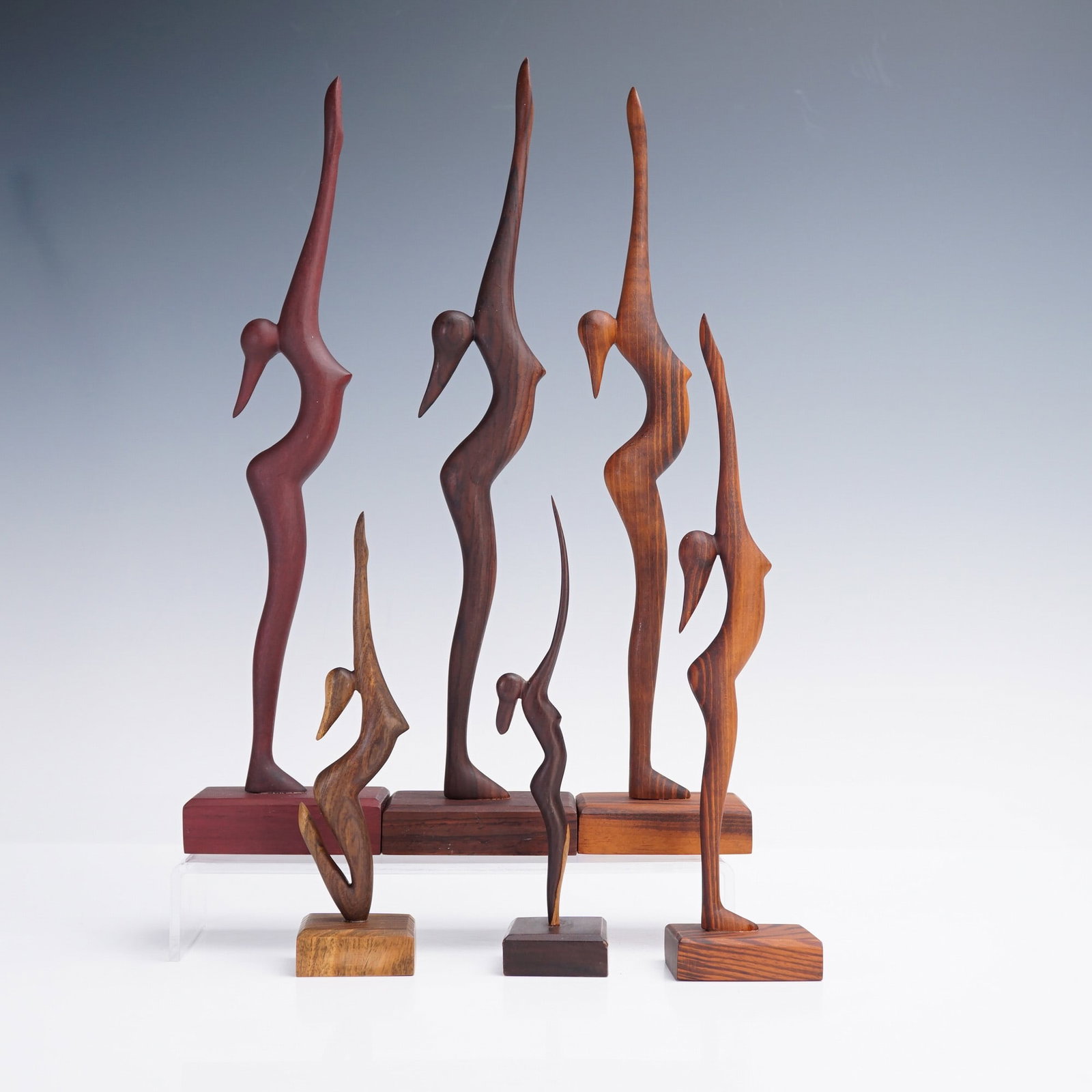 6pc Wooden Praying Women Figurines: A collection of six stylized wooden sculptures, each depicting an elongated abstract female figure in a prayerful stance with arms raised overhead. The set showcases variations in scale and wood tones