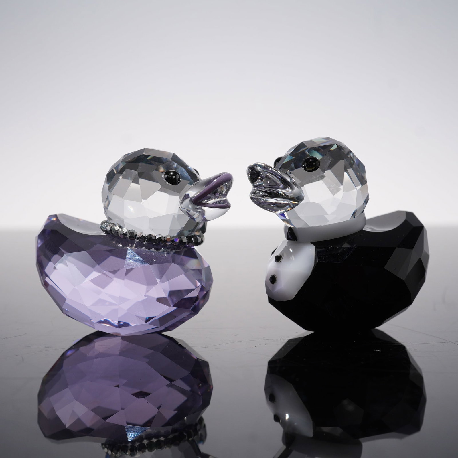Swarovski Happy Ducks Figurines, Sir and Lady Duck: Pair of Swarovski Happy Ducks, Sir and Lady Duck 1096733, featuring a groom in clear and black crystal with tuxedo detail and a bride in lavender crystal adorned with a beaded collar. Both display exc