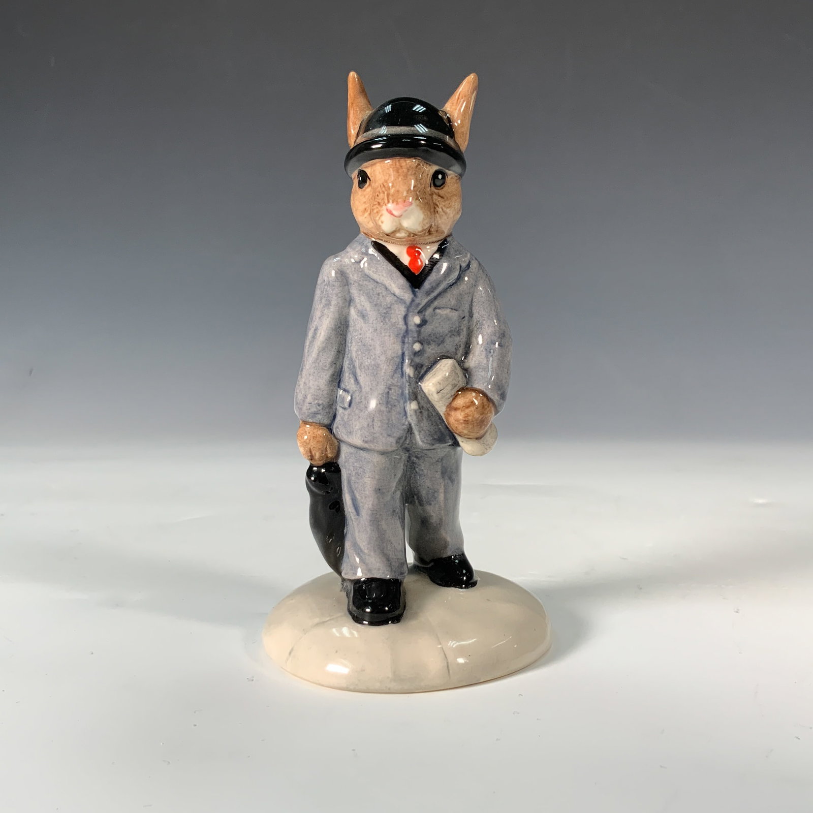 Royal Doulton Bunnykins Figurine, Businessman DB203: This Royal Doulton Bunnykins figurine, titled "Businessman" (DB203), features a rabbit dressed in a gray suit, black bowler hat, and polished shoes, holding a newspaper and umbrella. Designed by C. Da