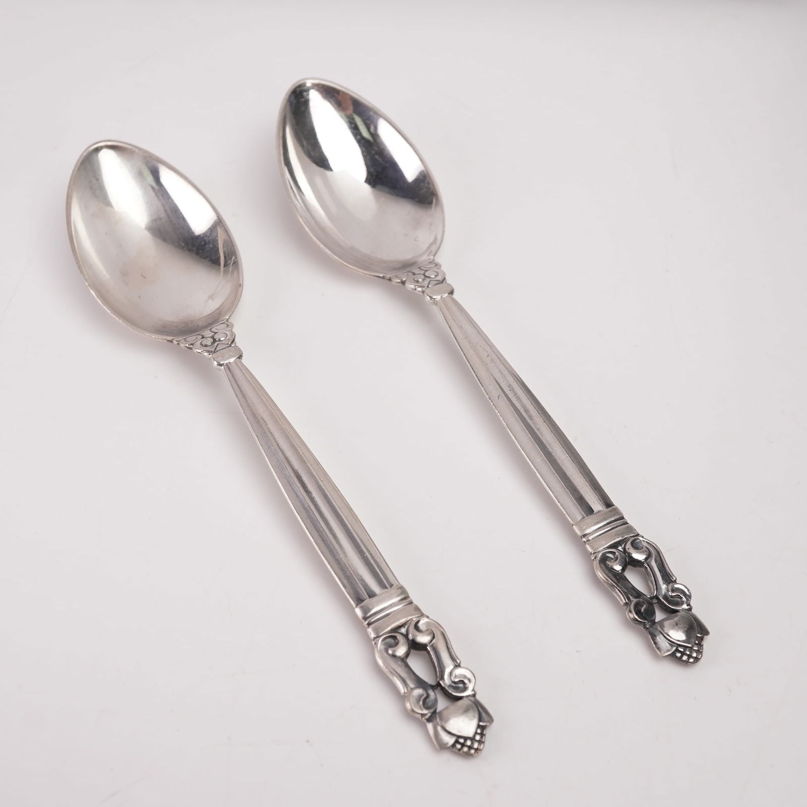 2pc Georg Jensen Sterling Silver Teaspoons, Acorn: A two-piece lot of Georg Jensen sterling silver teaspoons in the Acorn pattern, designed by Johan Rohde in 1915. Each marked Georg Jensen Sterling Denmark. The pattern features a fluted handle with sc