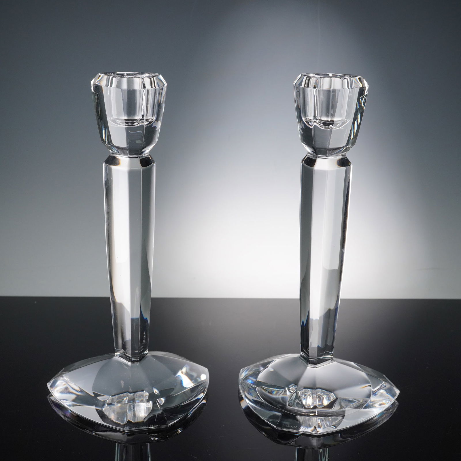 Tiffany & Co Pair of Crystal Candlesticks: A stunning pair of Tiffany & Co crystal candlesticks, crafted with sleek geometric faceting and modern lines that reflect light with brilliance. Each candlestick is finely cut with triangular bases an