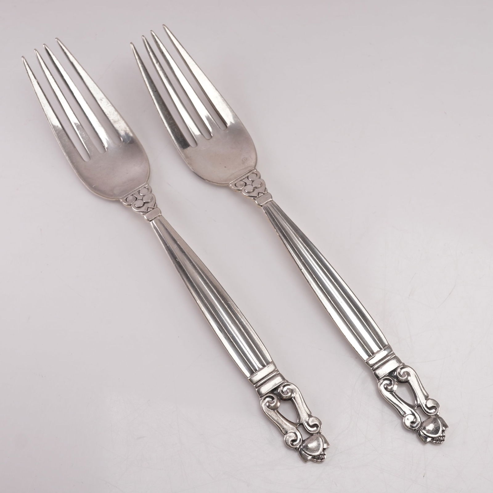 2pc Georg Jensen Sterling Silver Dinner Forks, Acorn: A two-piece set of Georg Jensen sterling silver dinner forks in the Acorn pattern, designed by Johan Rohde in 1915. Each marked Georg Jensen Sterling Denmark. The pattern features a fluted handle with