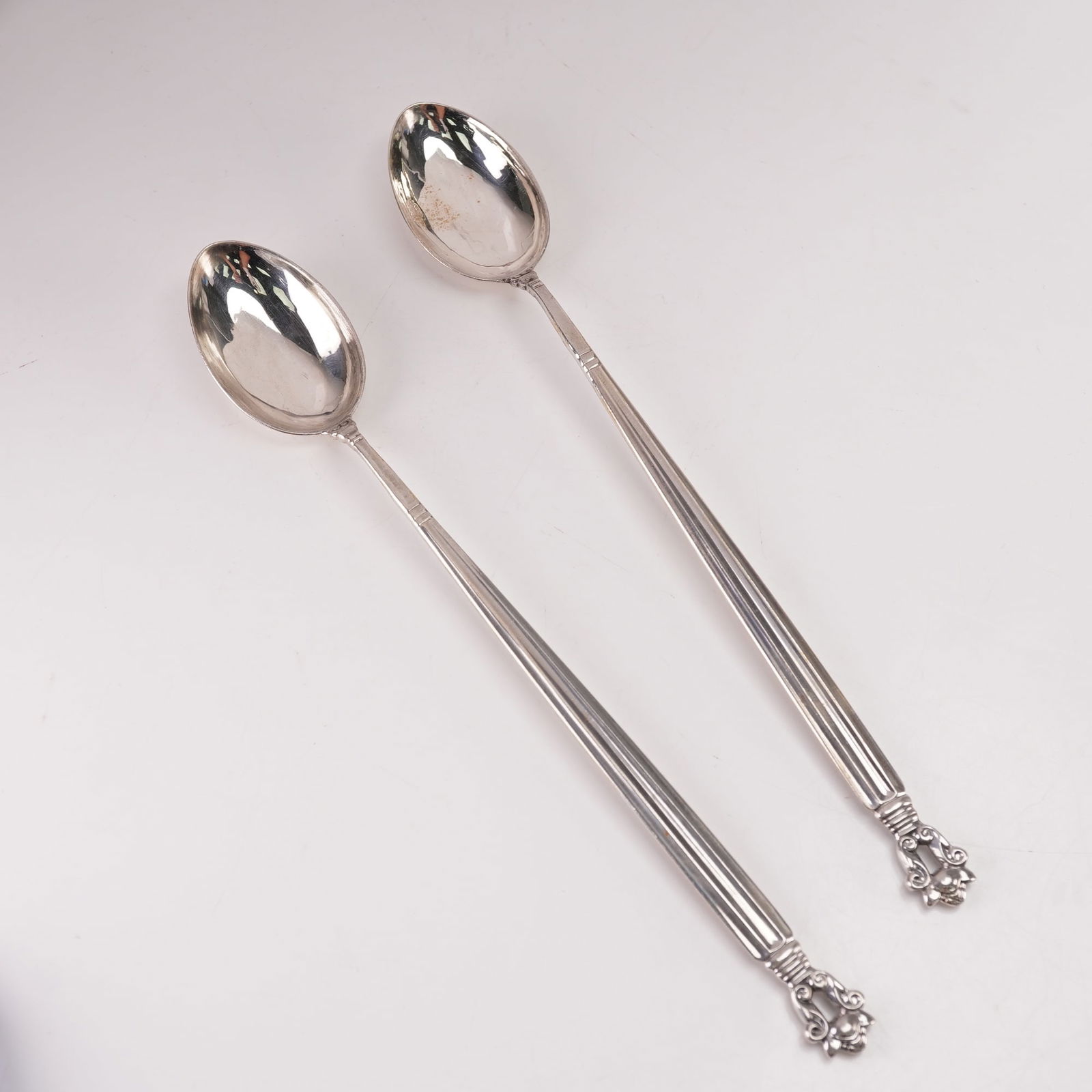 2pc Georg Jensen Sterling Silver Ice Tea Spoons, Acorn: Elegant two-piece Georg Jensen sterling silver iced tea spoons set in the distinguished Acorn pattern, originally designed by Johan Rohde in 1915. Each spoon features a long, graceful handle with refi