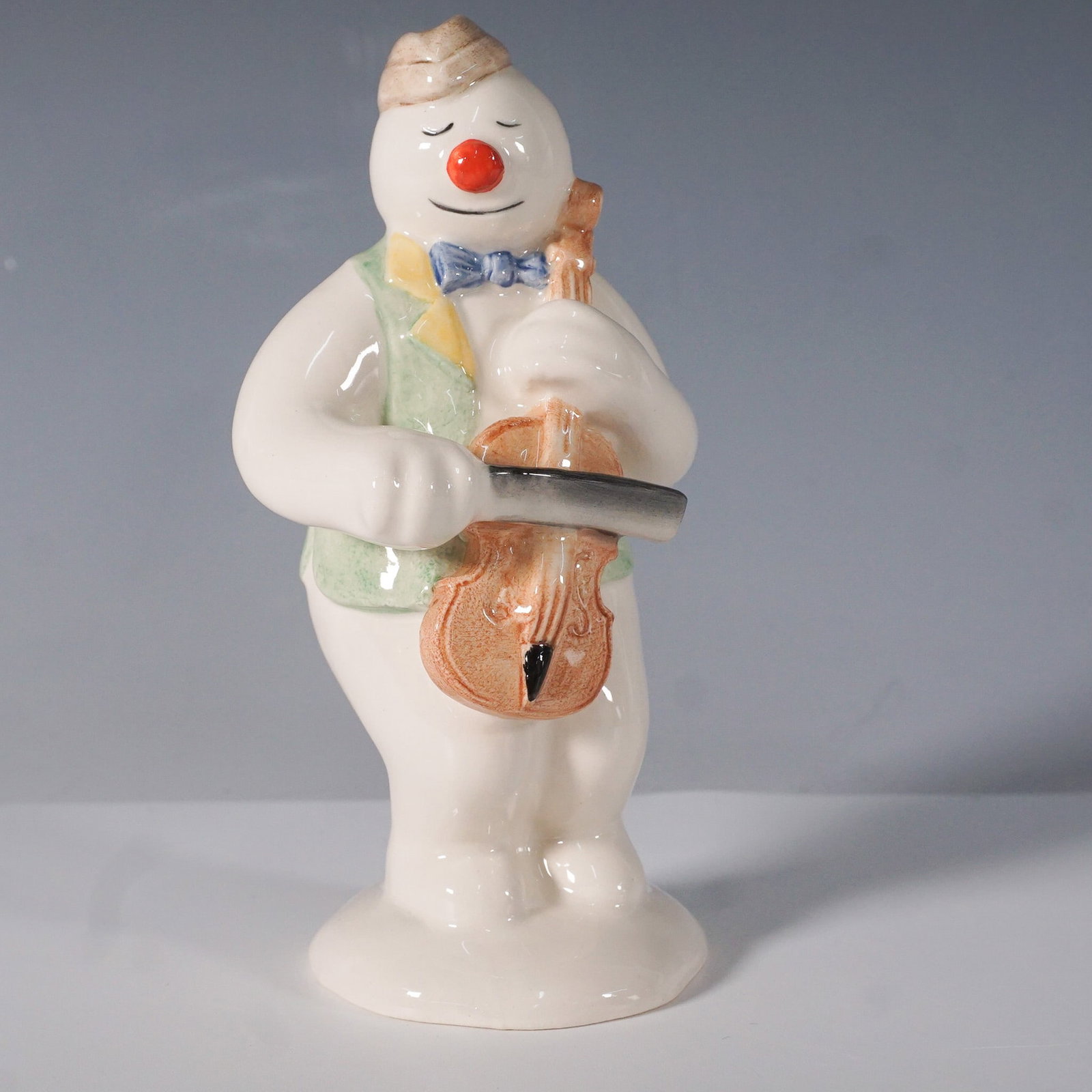 Royal Doulton "Cellist Snowman" Figurine DS17: Charming hand-painted Royal Doulton figurine from The Snowman Gift Collection, featuring the Cellist Snowman playing a violin. Inspired by Raymond Briggs' classic Christmas tale, this collectible is m