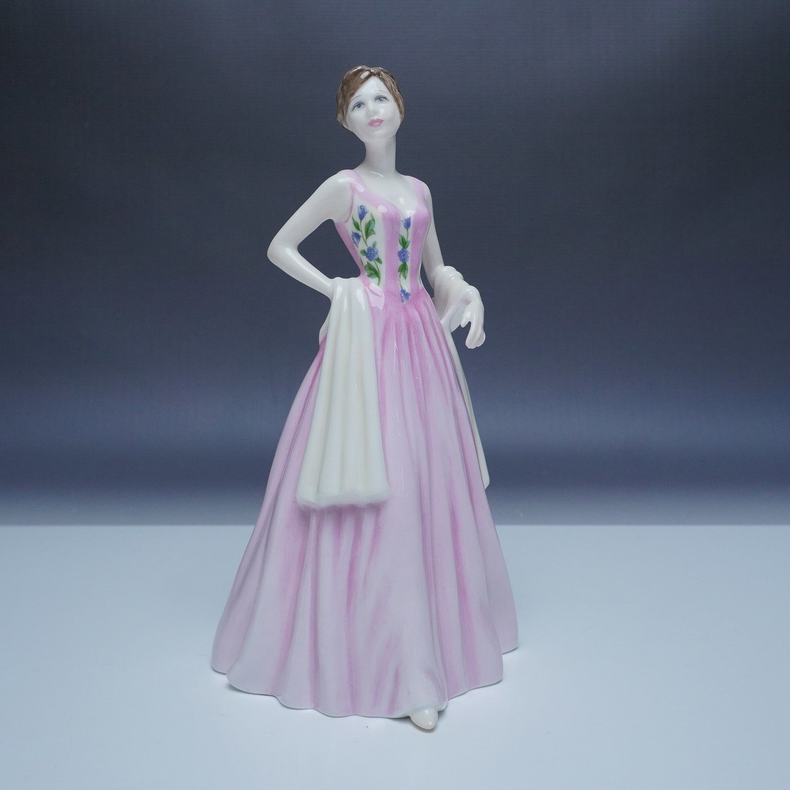 Royal Doulton HN 4520 April Figurine, Nada Pedley: This Royal Doulton bone china figurine, April (HN 4520), is part of the Classics collection and was designed by Nada Pedley. Introduced in 2000, this elegant piece portrays a graceful woman dressed in