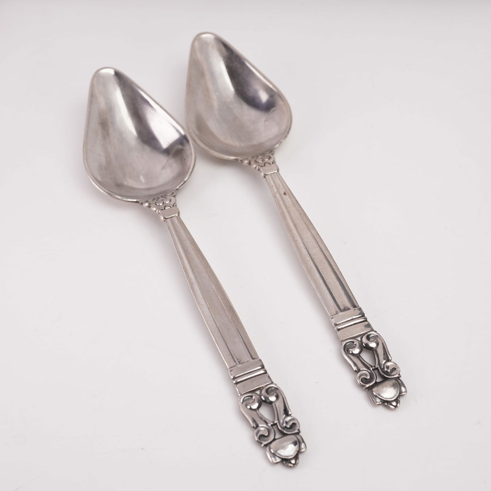2pc Georg Jensen Sterling Silver Grapefruit Spoons, Acorn: This elegant two-piece set of Georg Jensen sterling silver grapefruit spoons features the renowned Acorn pattern, originally designed in 1915 by Johan Rohde. Each spoon displays the distinctive teardr