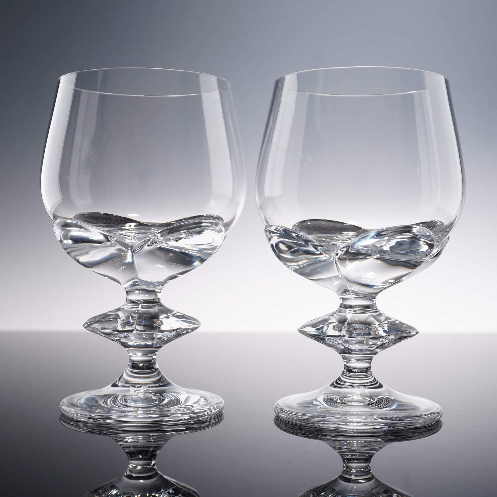 Pair of Lalique Crystal Sherry Glasses, Blois: Formerly part of the estate of Marie-Claude Lalique. Set of two clear crystal sherry glasses, each featuring a smooth bowl and a distinctive wafer stem. The underside of each glass is etched with Lali