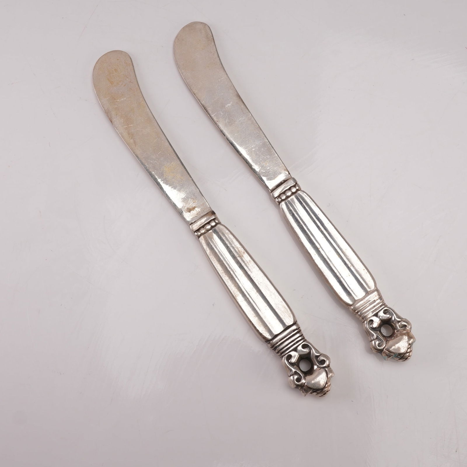 2pc Georg Jensen Sterling Silver Paddle Butter Spreaders, Acorn: A two-piece lot of Georg Jensen sterling silver hollow handle paddle butter spreaders in the Acorn pattern, designed by Johan Rohde in 1915. Each marked Georg Jensen Sterling Denmark. The pattern feat