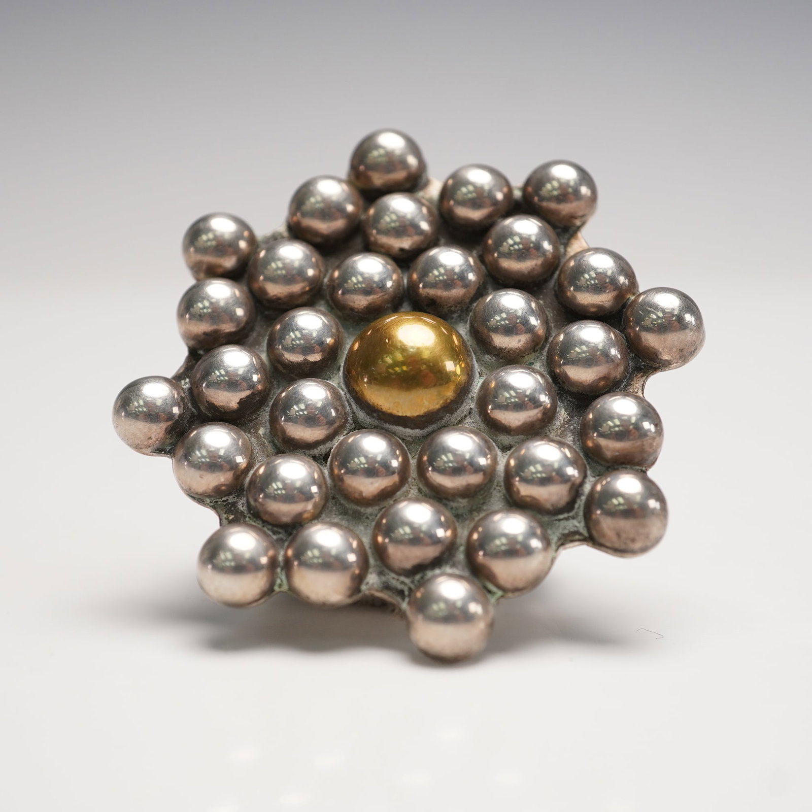 Mexican Sterling Silver Beaded Flower Brooch: Mexican sterling silver brooch designed in a bold beaded flower motif with a raised gilt center. The brooch is constructed with graduated silver beads radiating outward in a layered floral arrangement