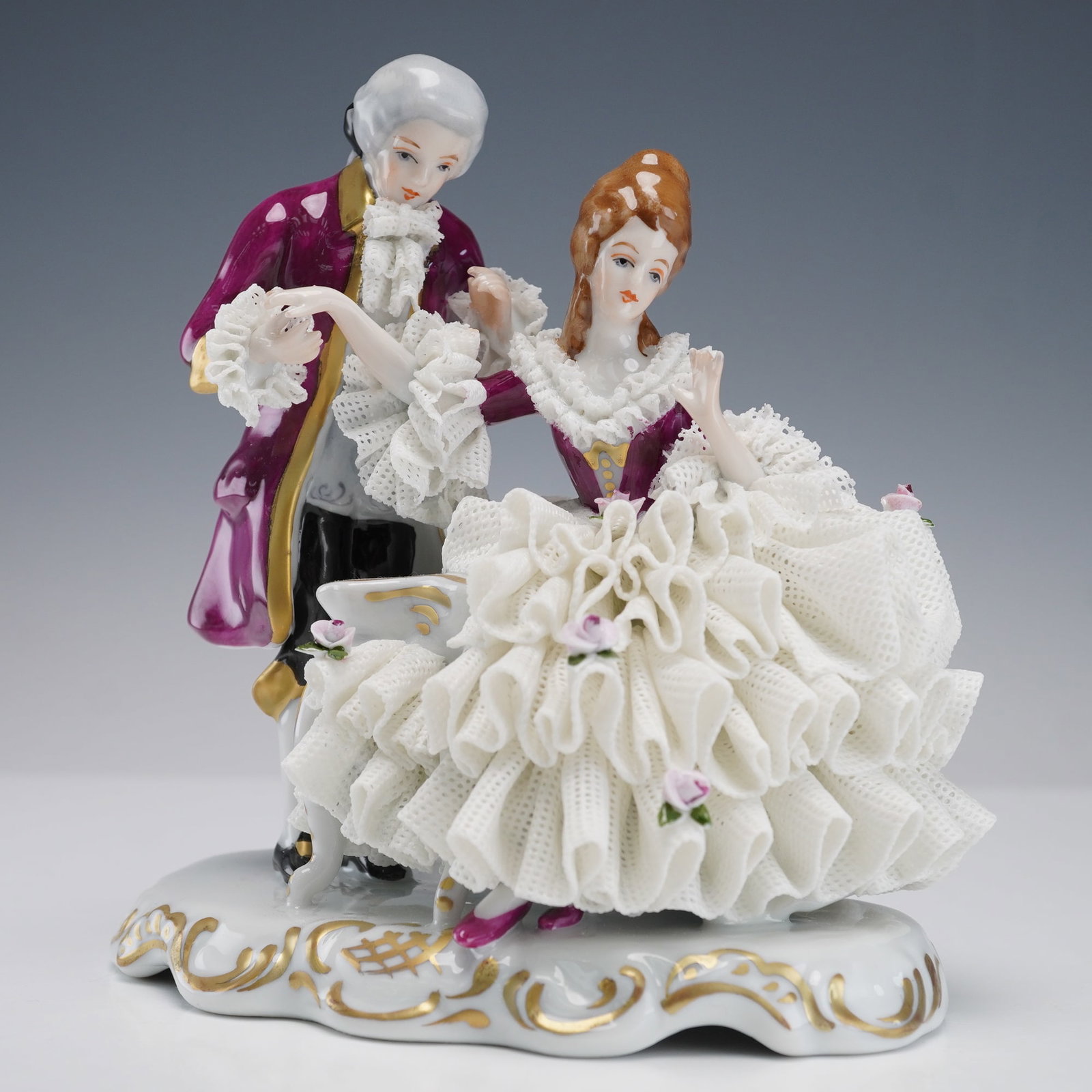 Dresden Germany Porcelain Lace Figurine, Courting Couple: Dresden Germany porcelain lace figurine depicting an 18th century courting couple. The finely modeled pair is dressed in period attire, with the lady seated in a white lace gown accented by delicate a