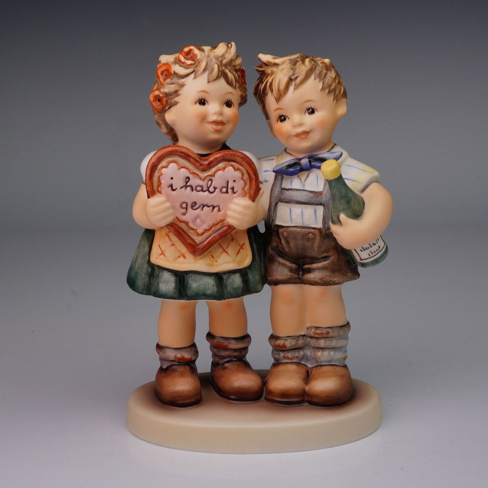 Goebel Hummel Figurine, Gifts of Love: Charming M.I. Hummel figurine titled Gifts of Love, model number 909, depicting a boy and girl standing together, the girl holding a heart-shaped gingerbread. Issued as an exclusive edition for the M.