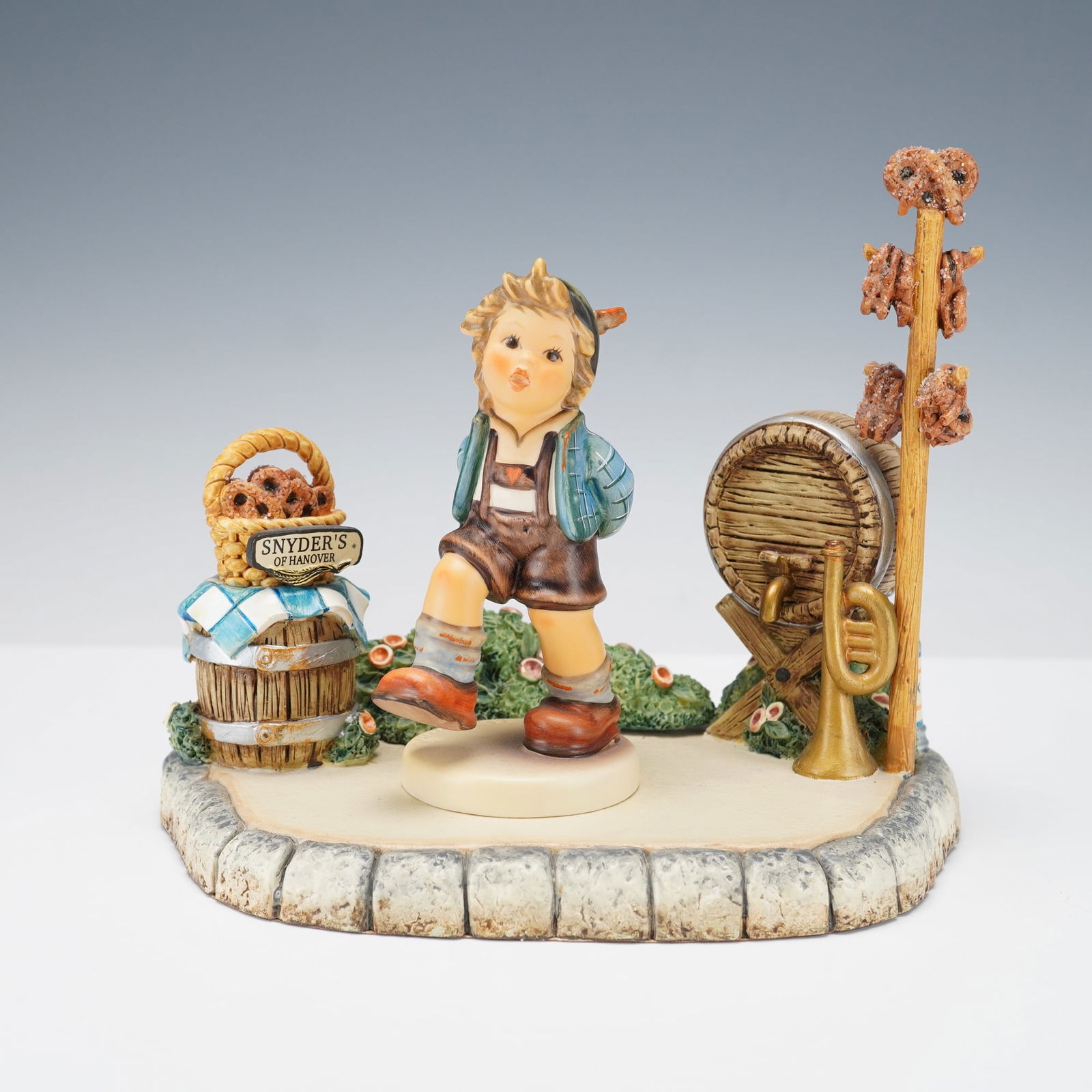2pc Goebel Hummel Figurine Set, Marktplatz w/ Alpine Dancer Limited Edition: Charming Goebel Hummel 2-piece figurine set titled Marktplatz, created in collaboration with Snyder's of Hanover. This limited edition features Alpine Dancer, a lively Bavarian boy in traditional atti