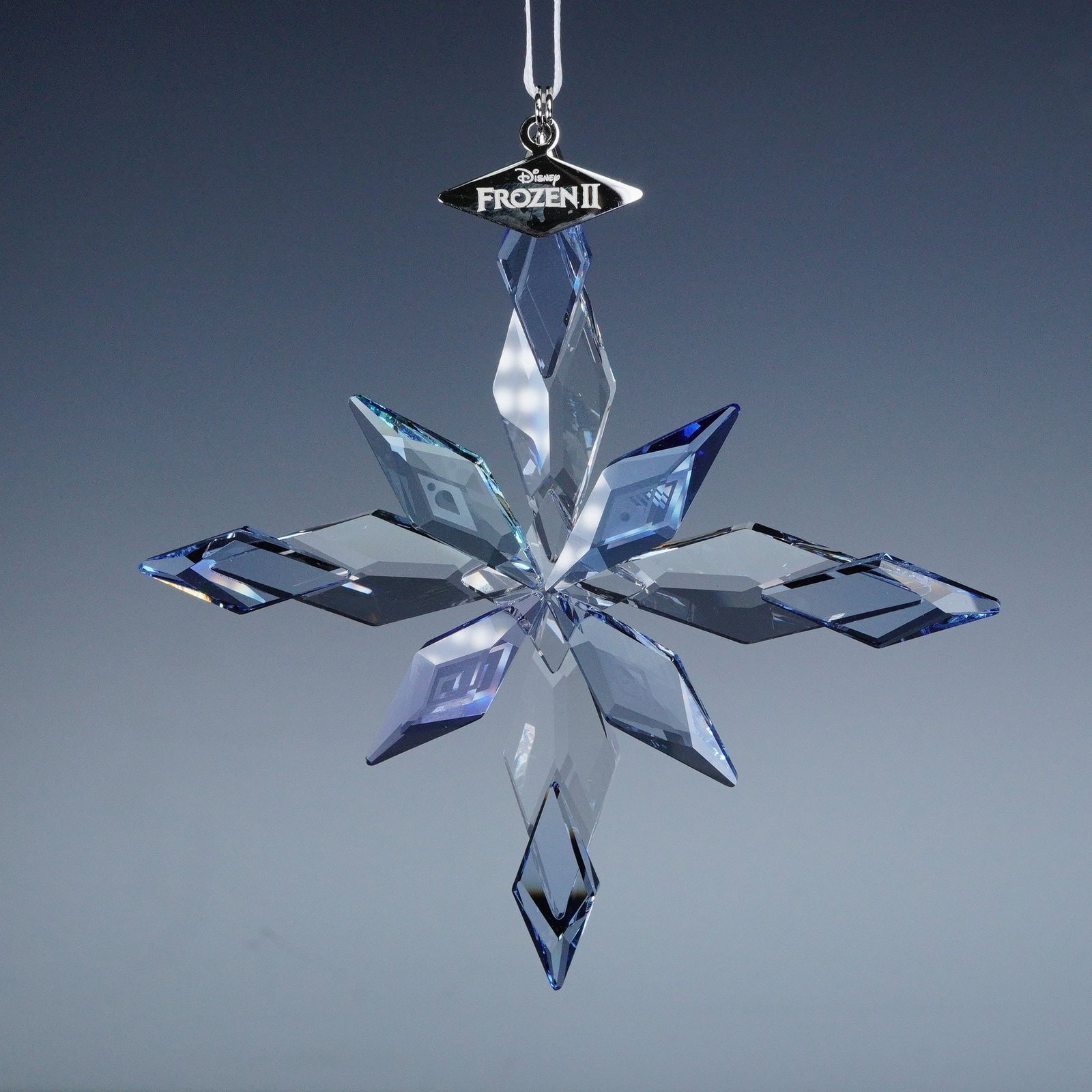 Swarovski Disney Frozen Snowflake Crystal Ornament: A dazzling Swarovski crystal ornament inspired by Disney's Frozen 2. Shaped as an elegant snowflake, this piece sparkles with finely cut facets in icy blue tones that capture the spirit of the film. T
