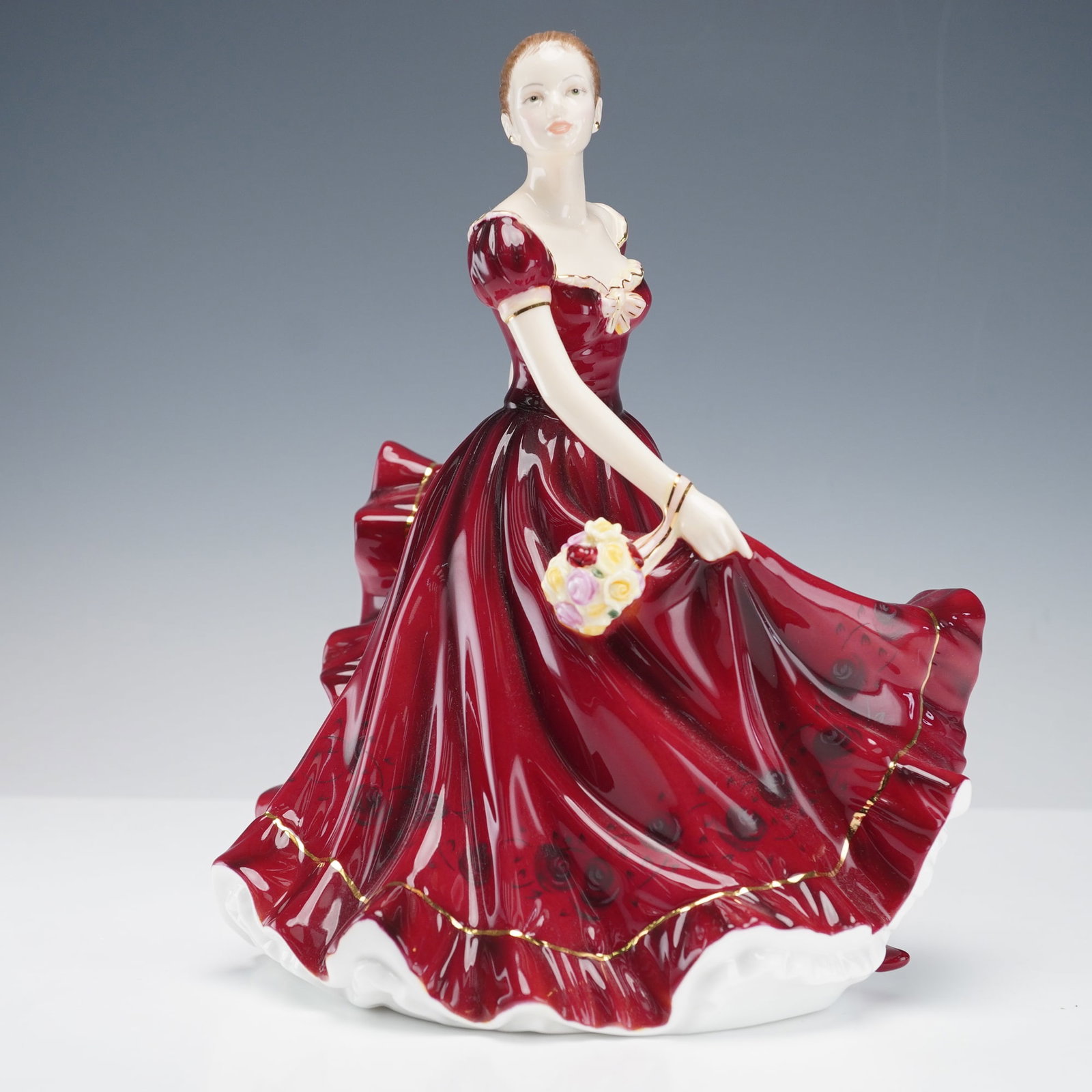 Royal Doulton 2010 Figurine of the Year Sophie HN5376: Royal Doulton porcelain figurine titled Sophie, the 2010 Figurine of the Year. The piece depicts a young woman in an elegant flowing gown in shades of red and cream, holding her skirt delicately as sh